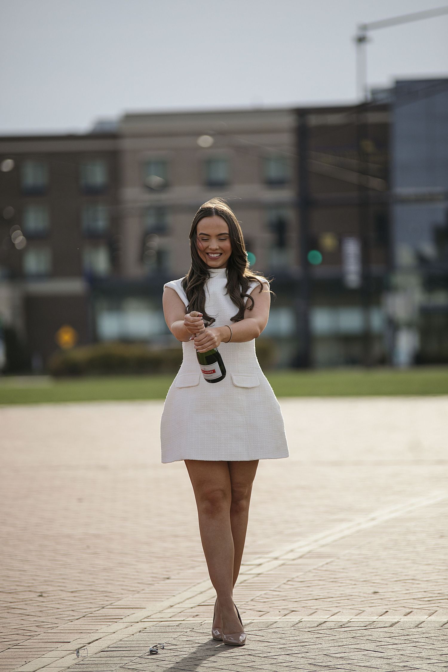 A series of five photos showing someone in a white dress walking and posing outdoors on paved ground.