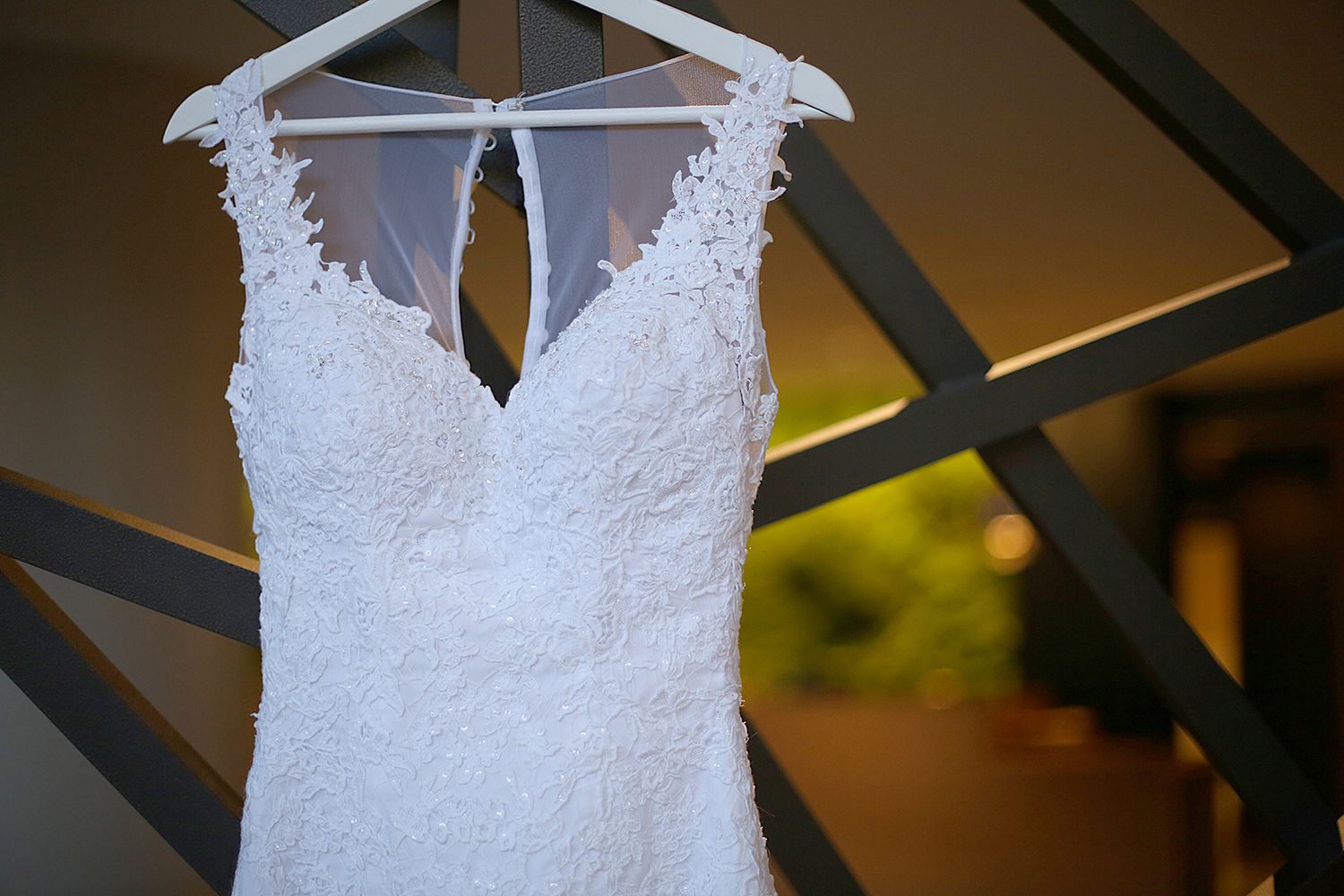 Detailed lace wedding dress hanging on display showing intricate white beadwork and keyhole back. kWedding Photographer in Cleveland Ohio