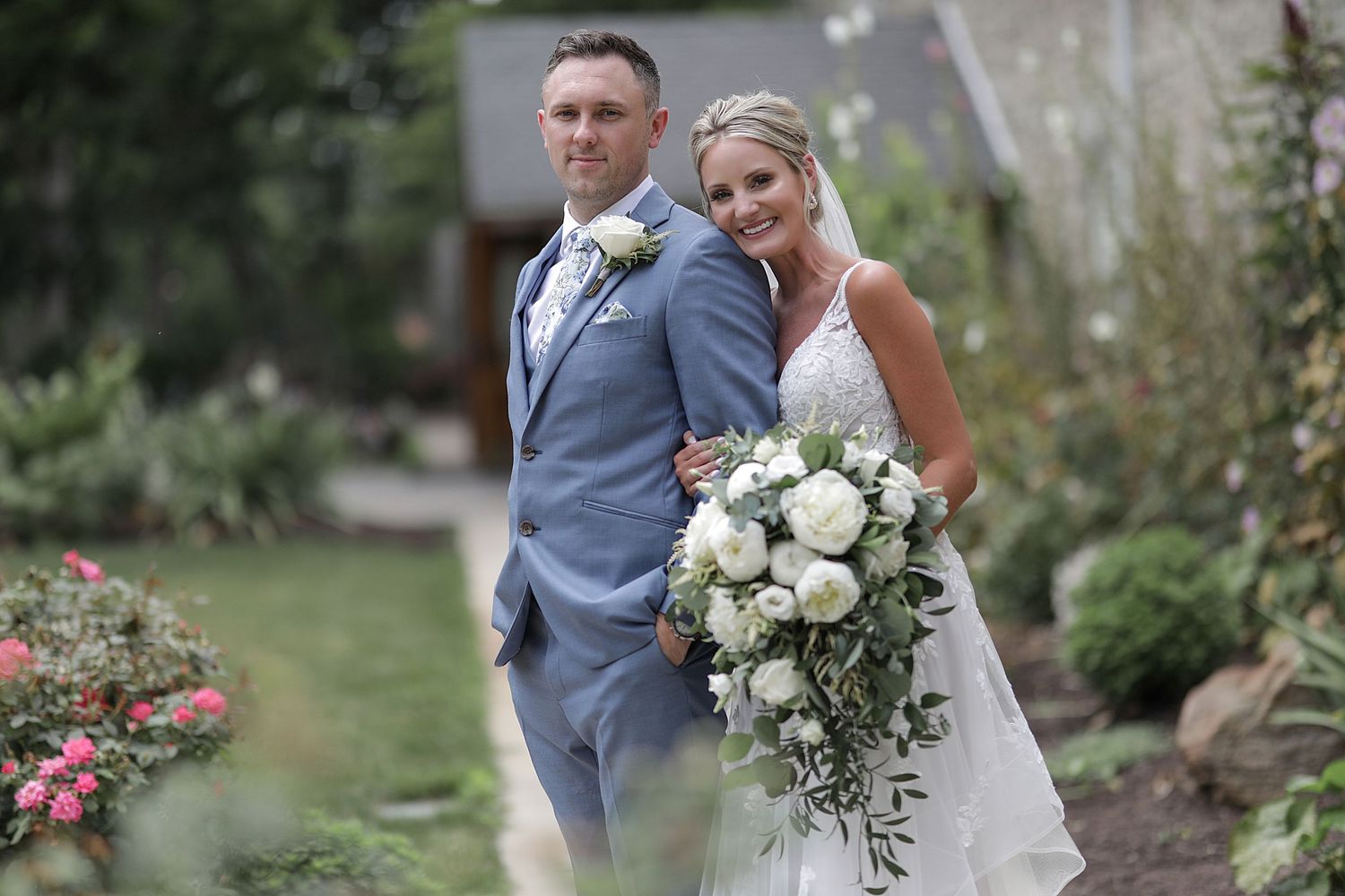 Elegant wedding couple poses in garden setting  and white floral bouquets. Destination wedding photographer. Cleveland wedding photographer.