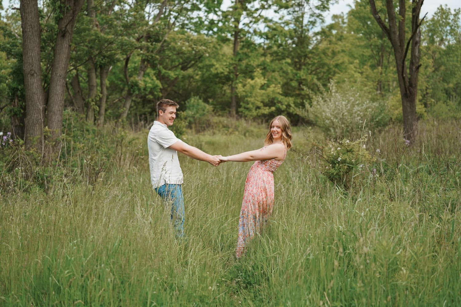 Dog playing with two people in a grassy meadow area during warm summer day.
