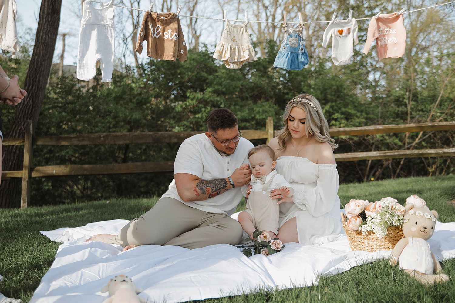 A romantic picnic spread with soft blankets and pillows sits in a lush garden setting with floral decor and treats.