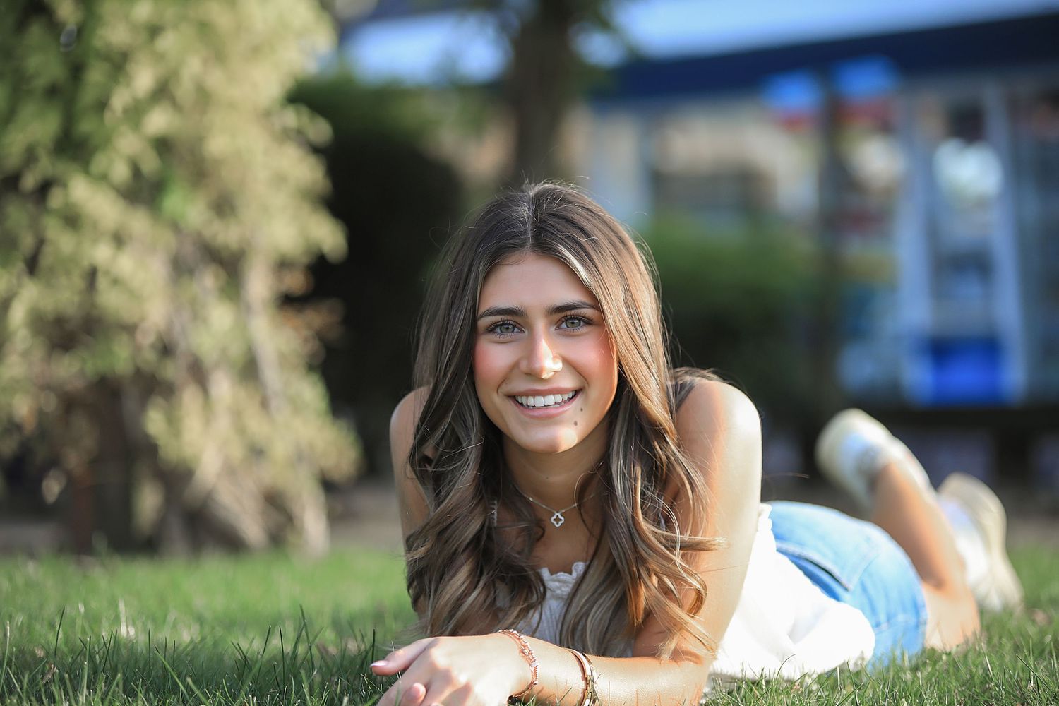 Woman with long brown hair relaxing outdoors on grass during sunny summer day.