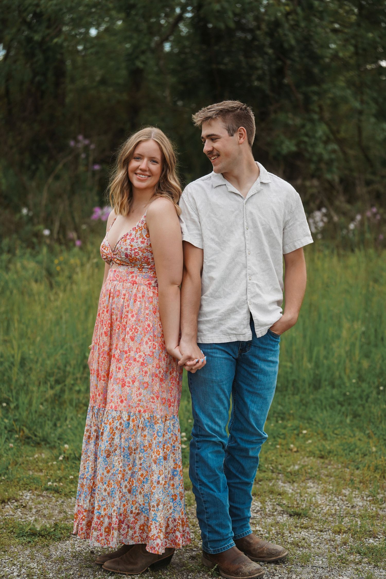 A couple in jeans and summer attire share romantic moments together in a grassy outdoor setting.