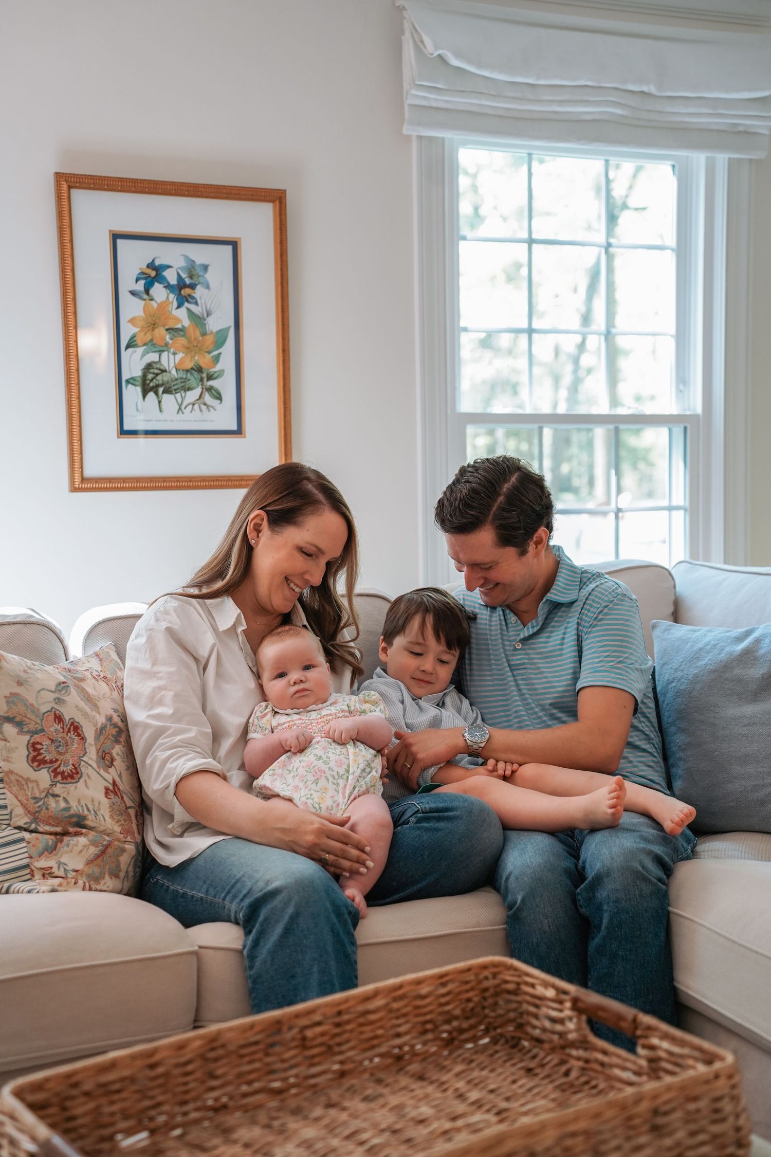 A family shares a tender moment together on their couch in a cozy living room with natural light from a window.