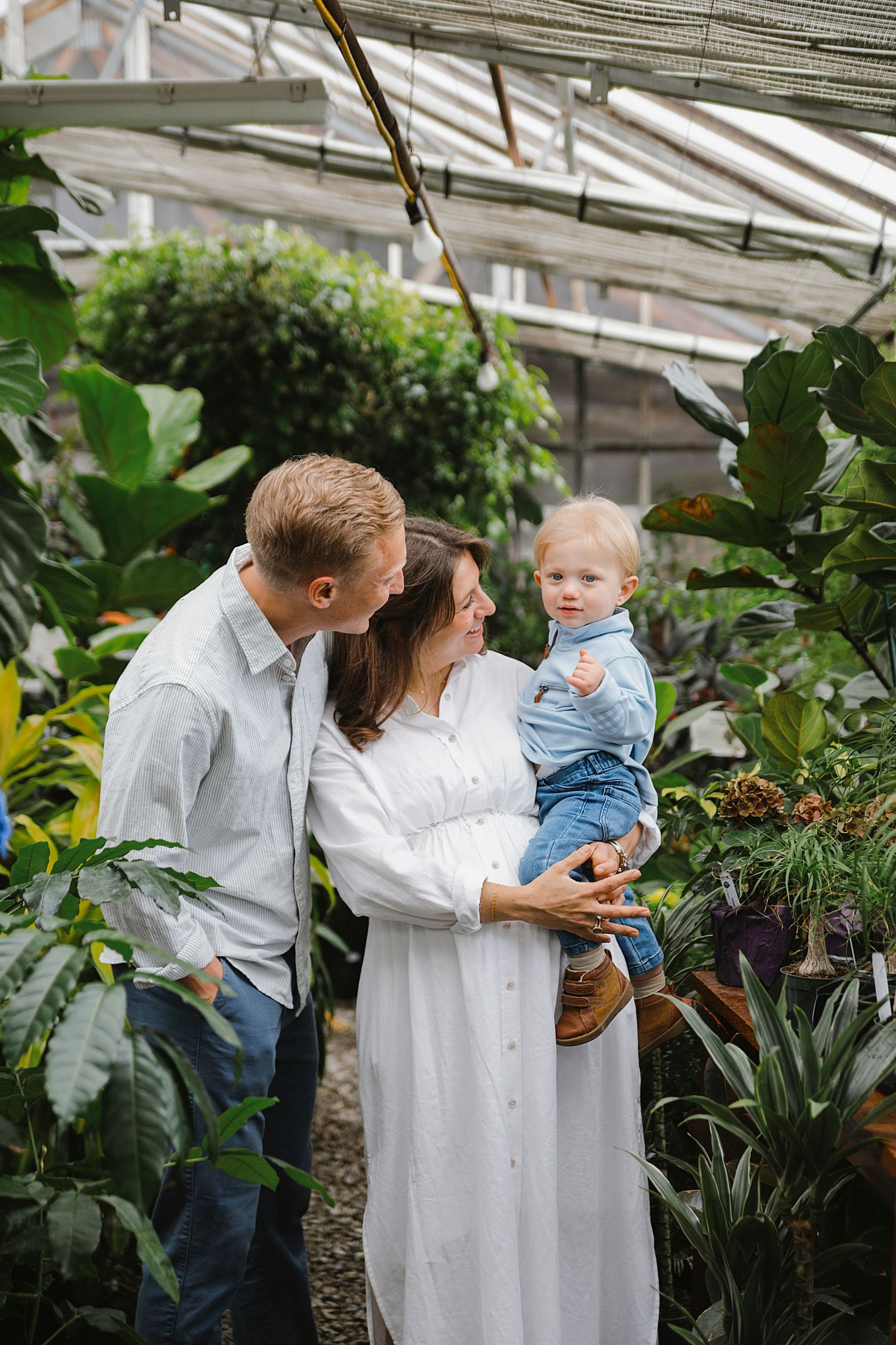 A tender family moment captured in a greenhouse surrounded by tropical plants and natural light.  Family Photography in Medina Ohio.