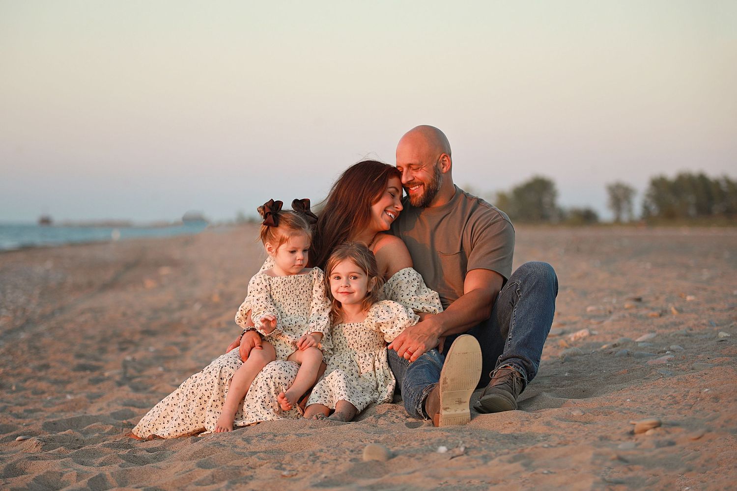 Family sitting together on beach at sunset in coordinated neutral outfits.  Family Photography in Mentor Ohio