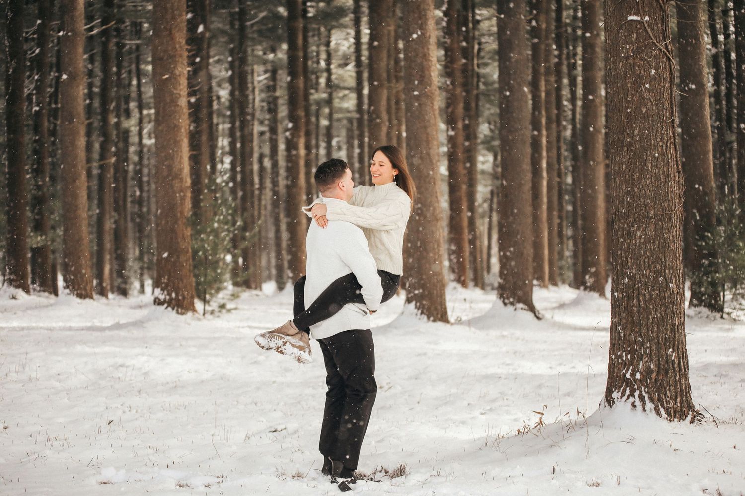 A romantic winter forest scene with two people embracing among snow-covered pine trees.