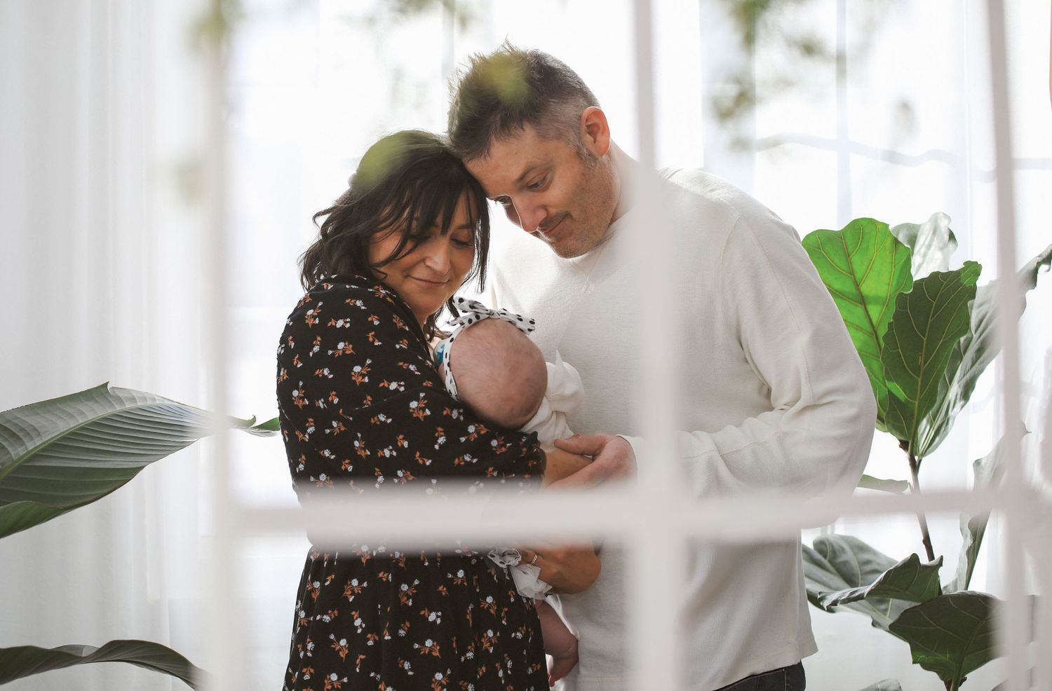 A couple in casual attire shares intimate moments together in a bright, minimalist interior setting.