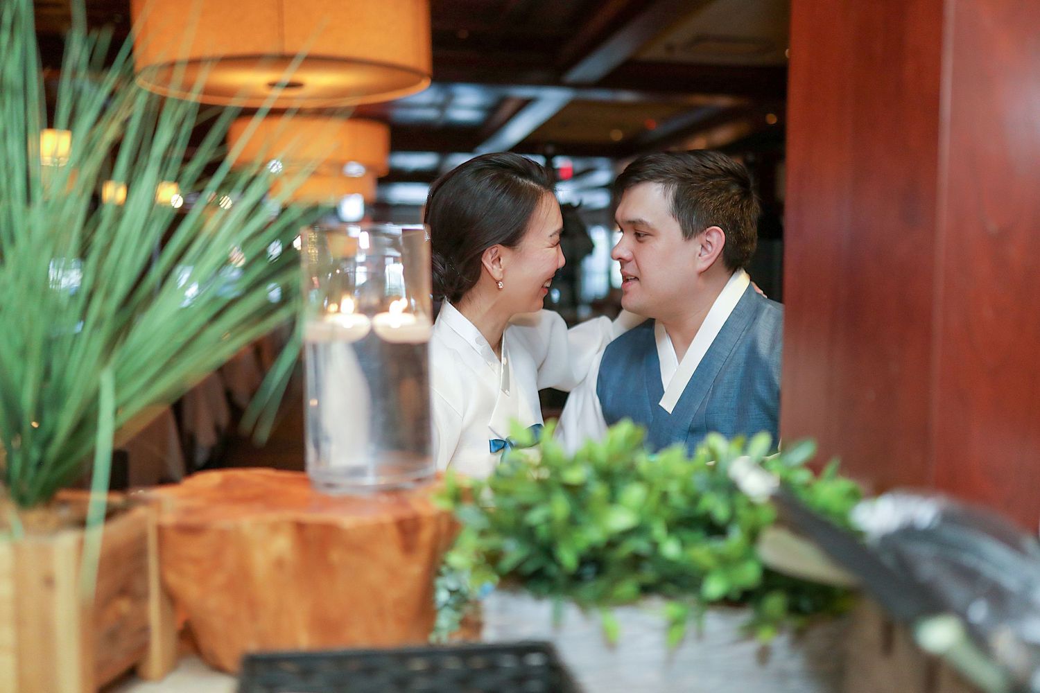 A romantic restaurant scene with lush greenery and warm lighting creates an intimate dining atmosphere.