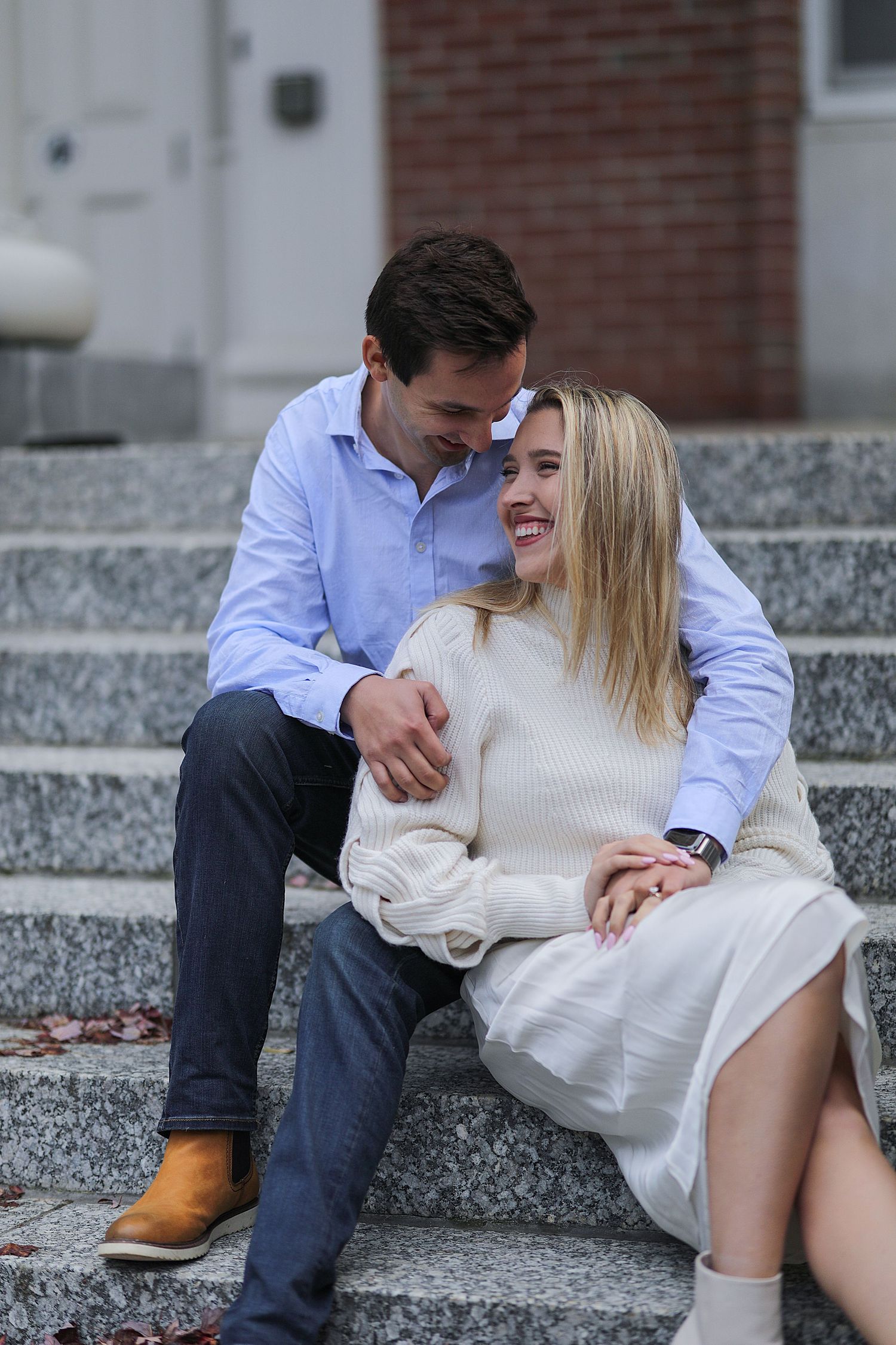 A couple shares an intimate moment while sitting on granite steps in a romantic outdoor photo series.