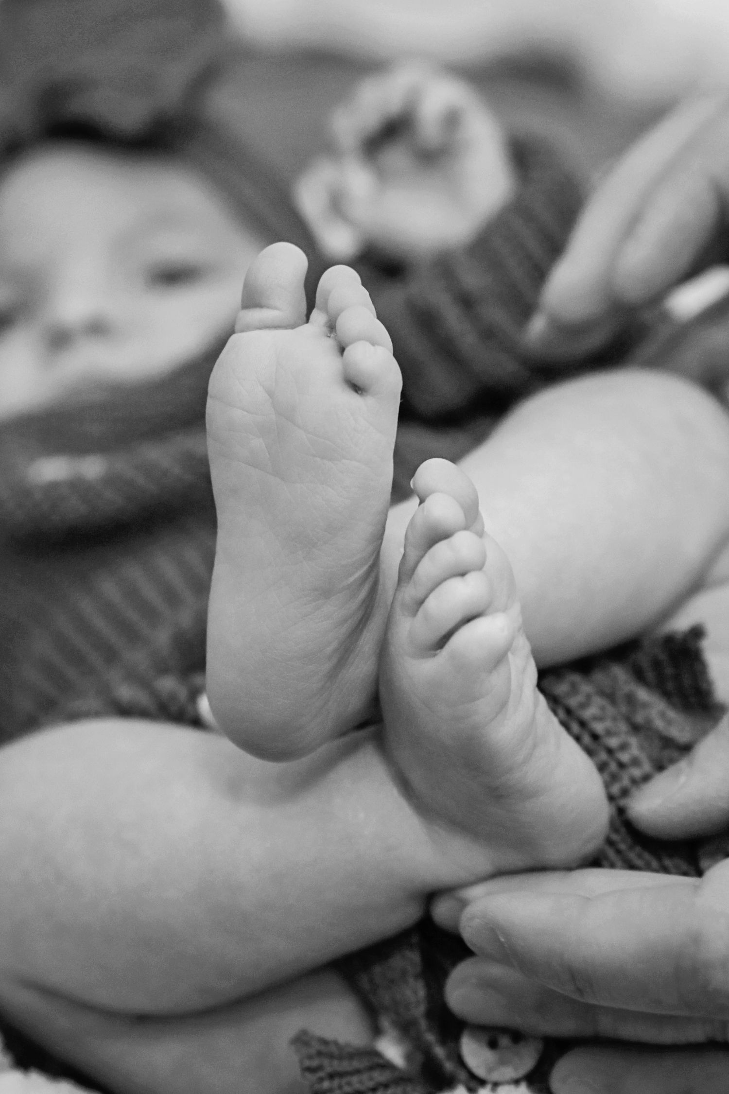 A series of black and white photographs showing tiny baby feet and toes against a soft textured background.