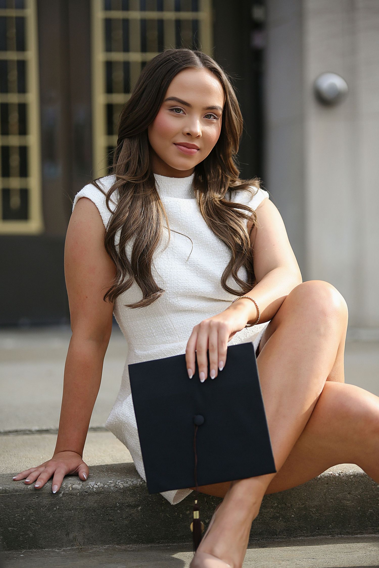 A person in a white sleeveless top and dark shorts poses on concrete steps in an outdoor photoshoot series.