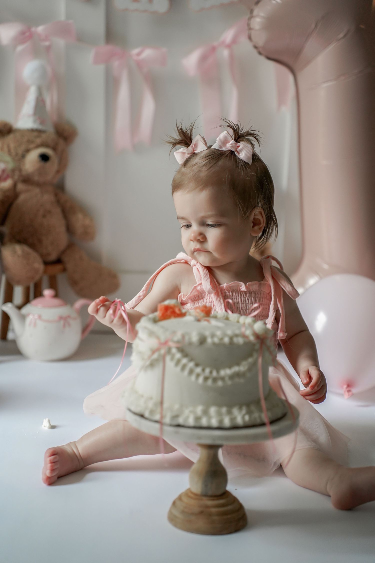 A professional cake smash photography session featuring a mint green cake and soft pink decor for a baby's milestone celebration.