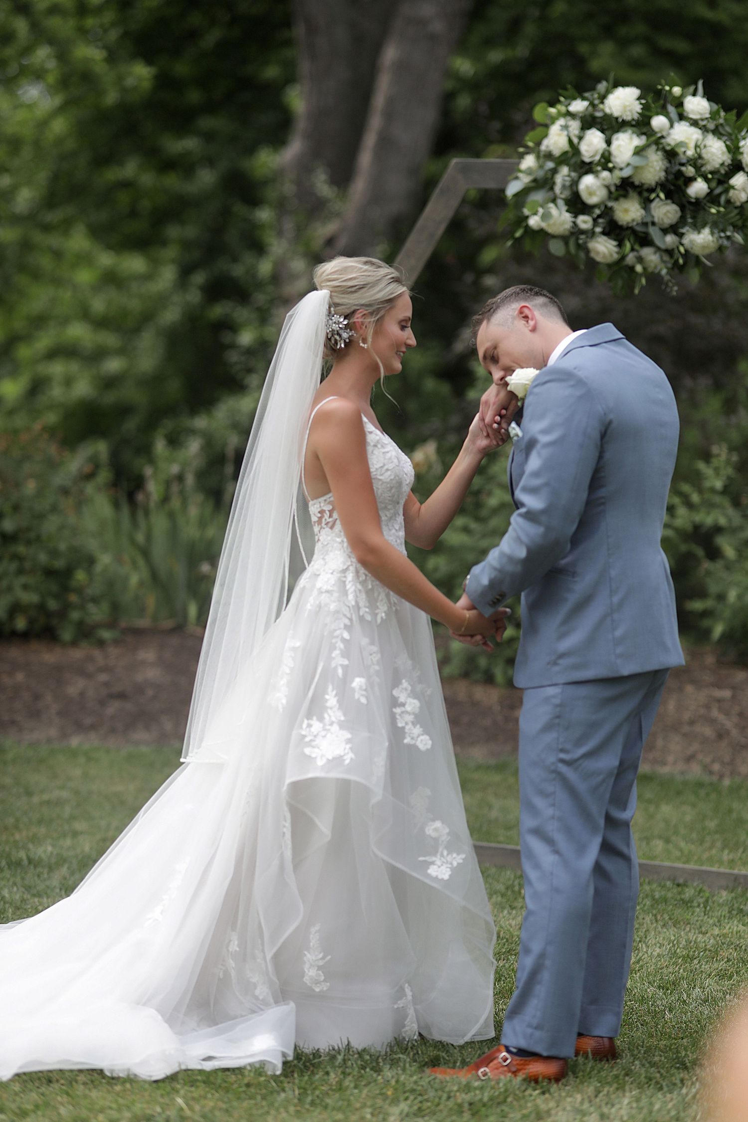 Emotional first look sequence between bride and groom in a garden setting.