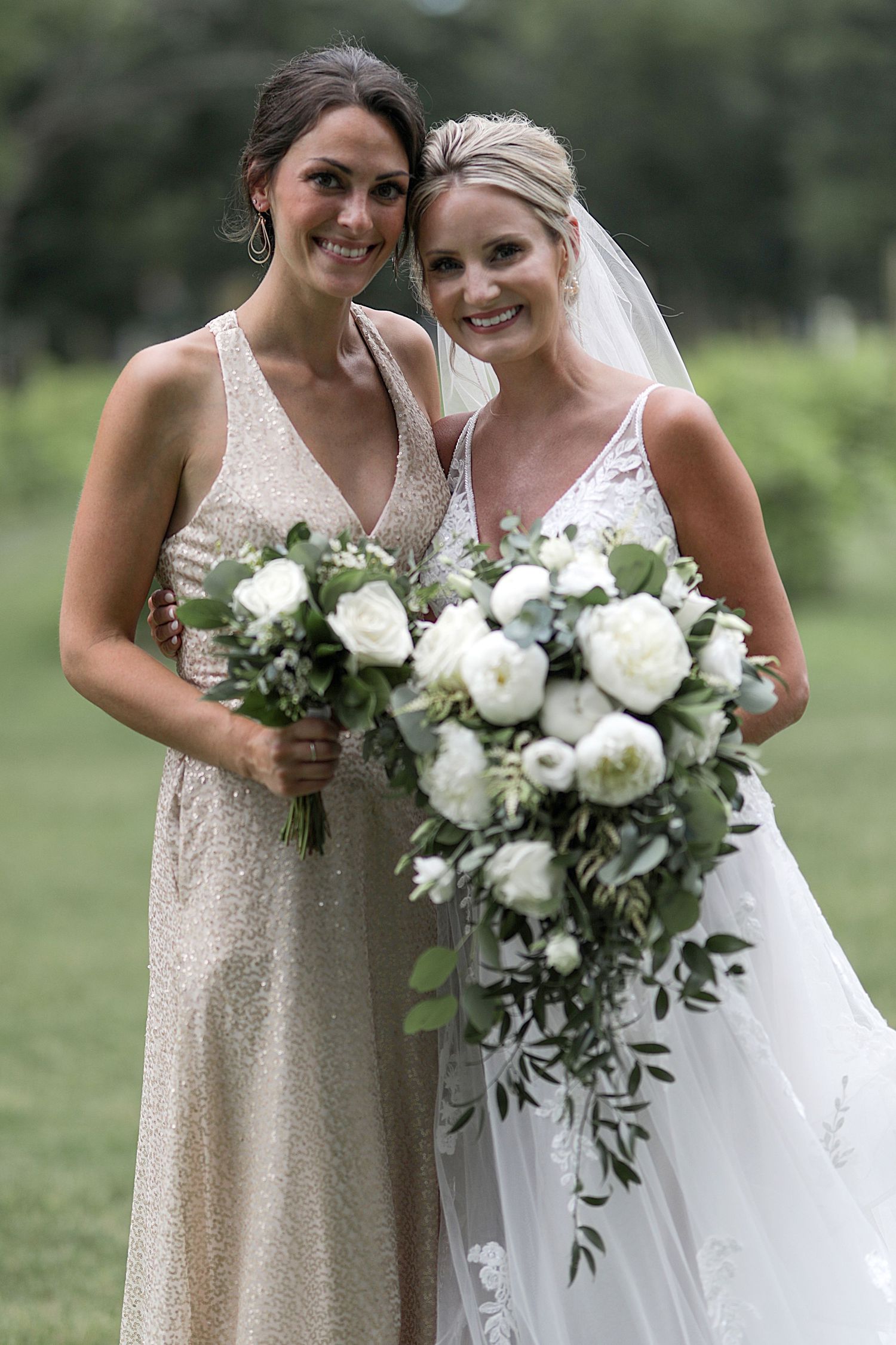 Bridesmaids in sparkly dresses holding white floral bouquets next to bride in wedding gown.