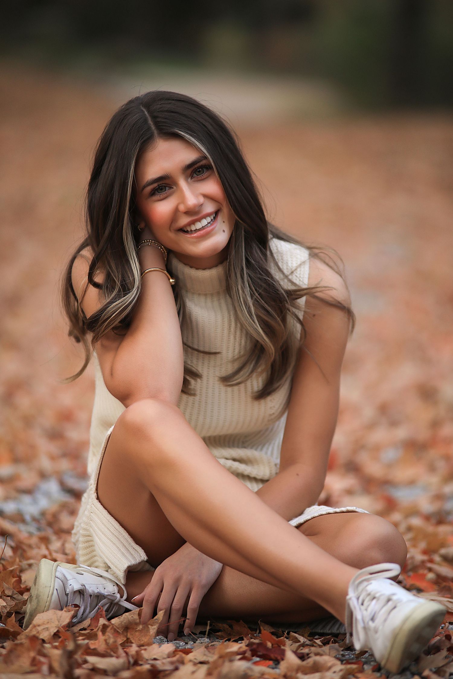 A series of autumn portraits showing someone in a cozy sweater laying among fallen orange and brown leaves.