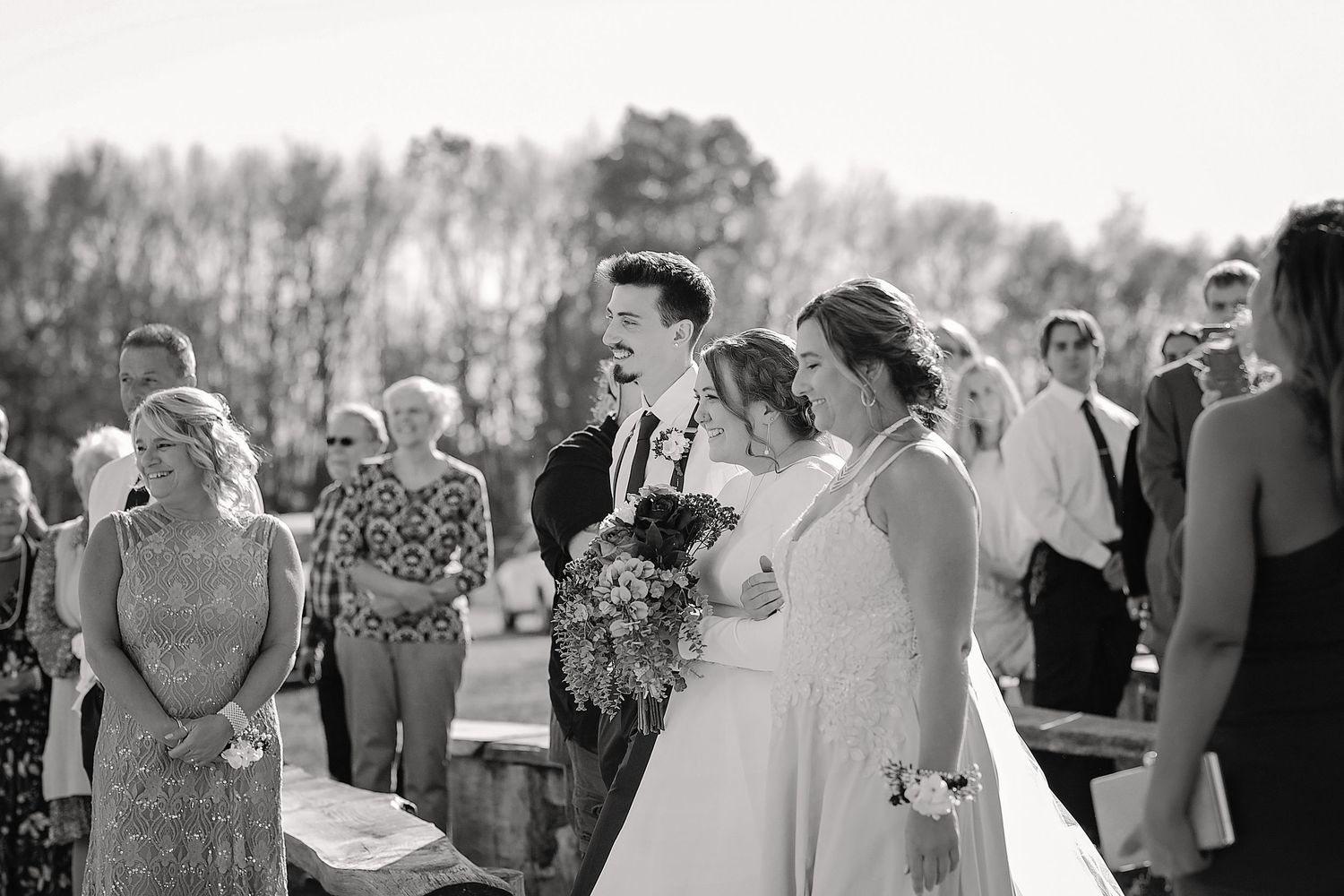 Wedding guests gather outdoors to celebrate during an autumn ceremony.
