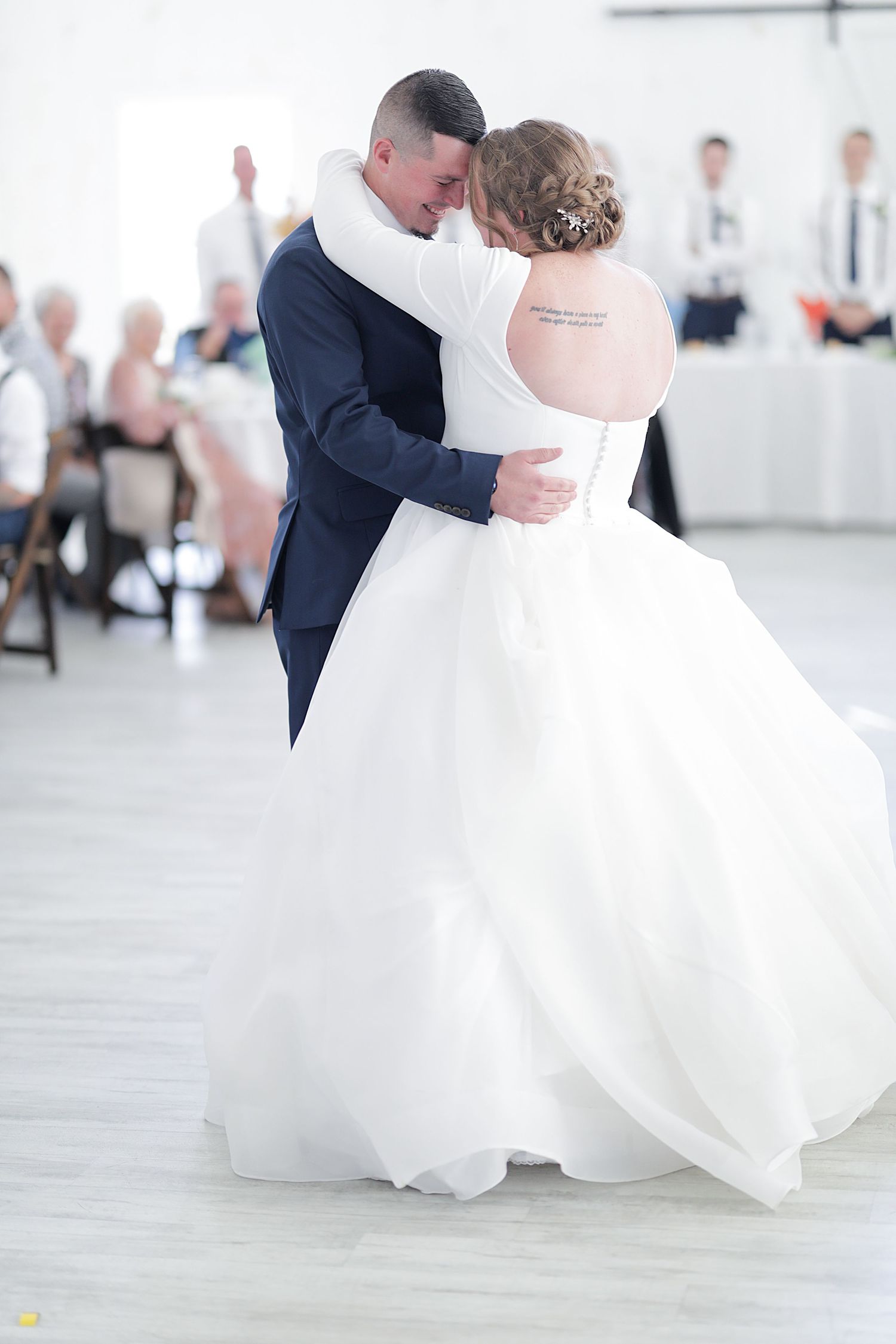 Couple shares romantic first dance in bright white reception venue.