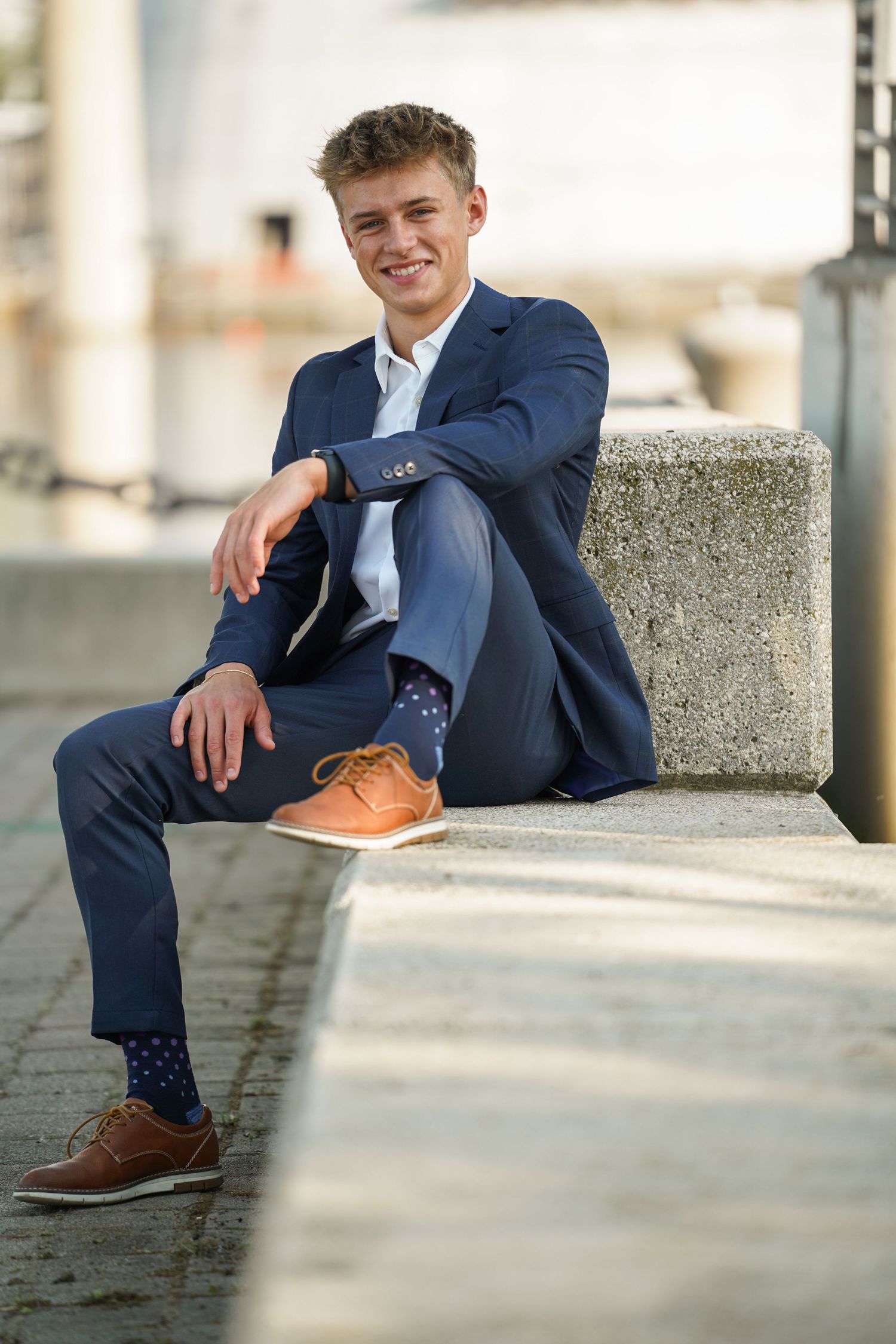 Close-up view of brown leather dress shoes paired with a navy suit while sitting on stone steps.