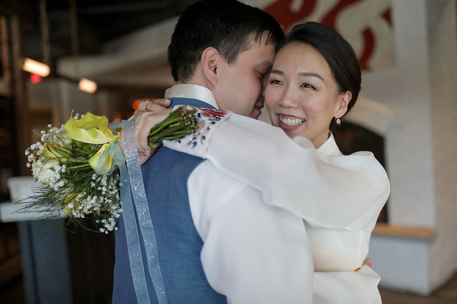 Two people sharing a joyful embrace during a wedding celebration in an indoor venue.
