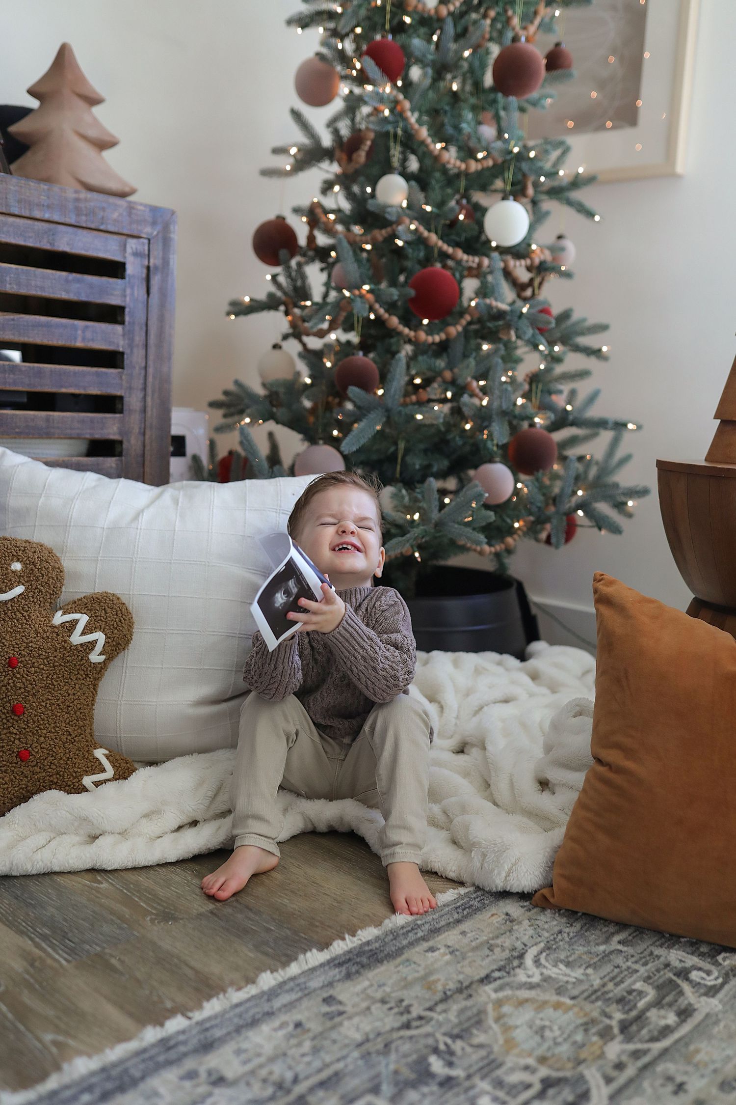 A series of photos showing someone lying on the floor near a decorated Christmas tree and white blanket.