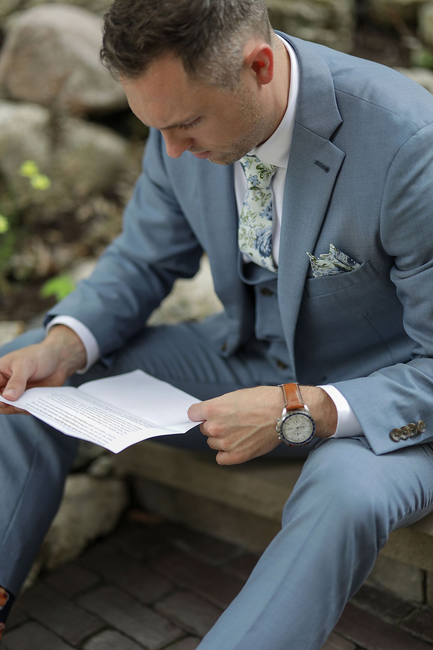 Person in light blue suit reading document while seated outdoors. Cleveland wedding photographer.