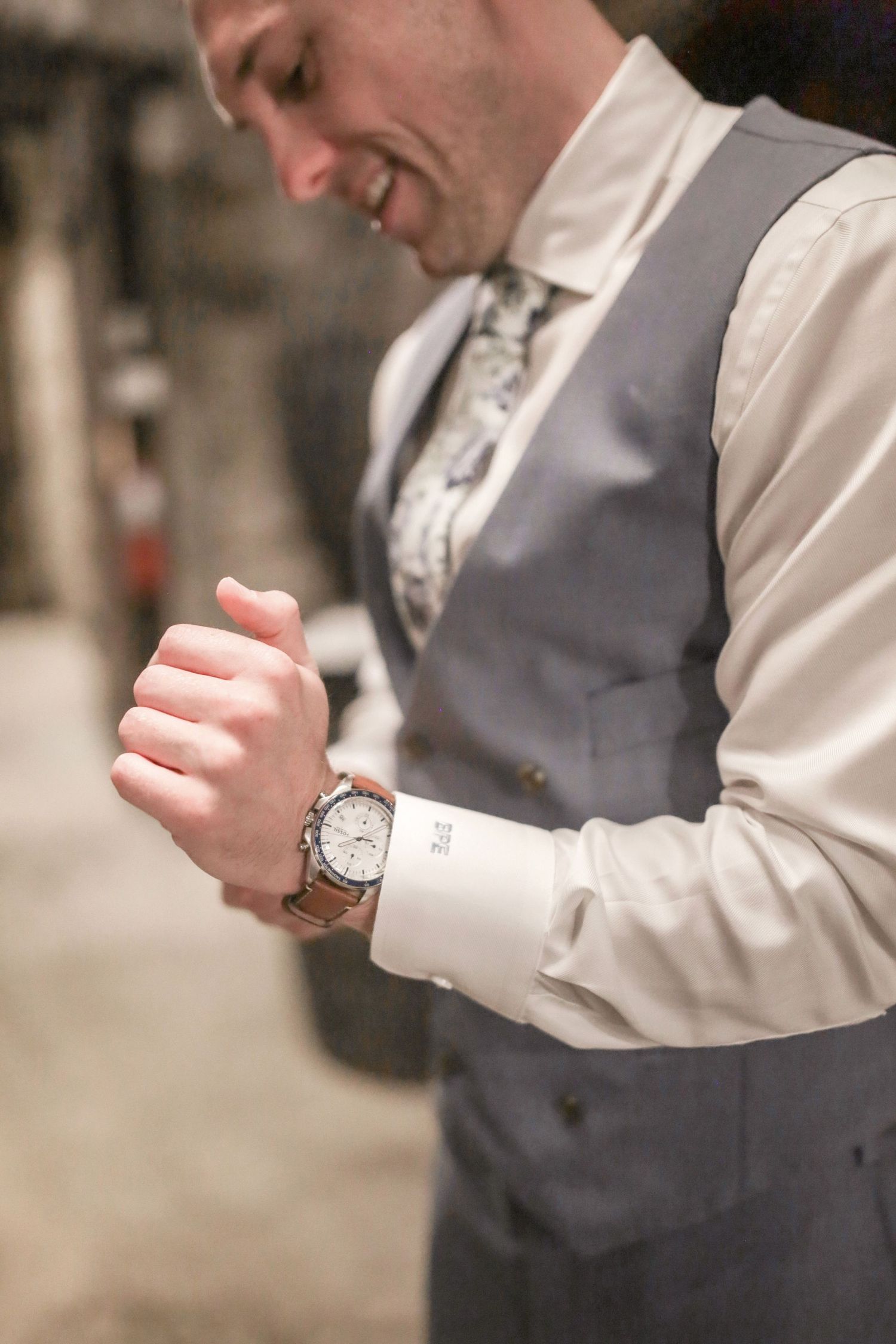 Close-up detail of a wristwatch and grey suit sleeve during wedding preparations.