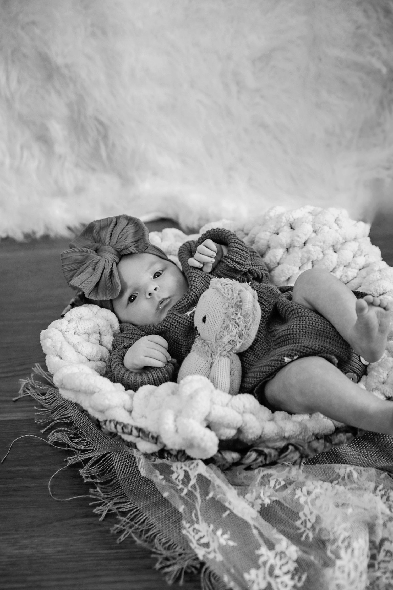 A black and white photo series showing a person lying down among soft cotton-like materials and snowflake decorations.