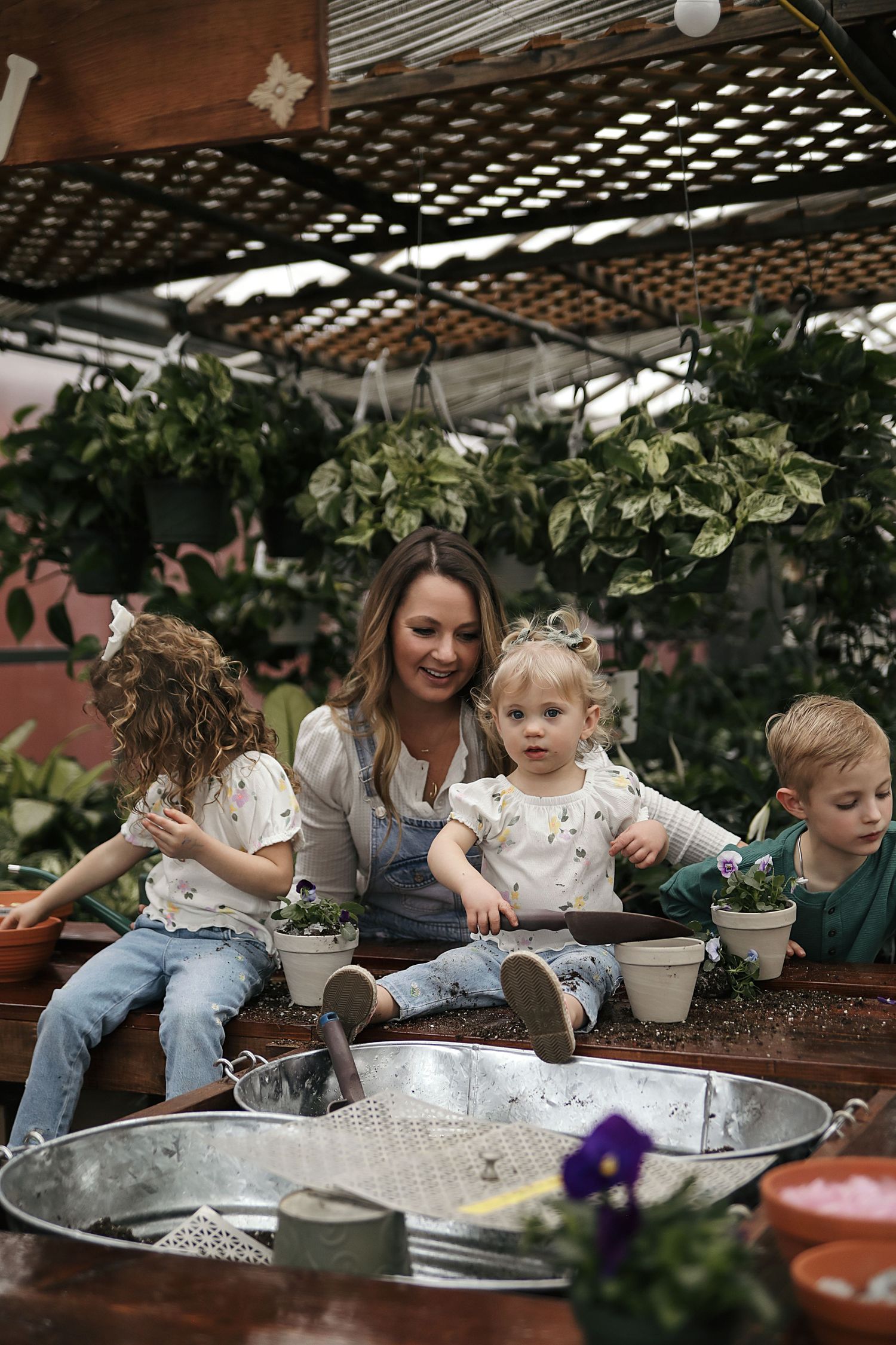 Family enjoying a fun moment while gardening together at an outdoor wooden planter box under pergola cover.