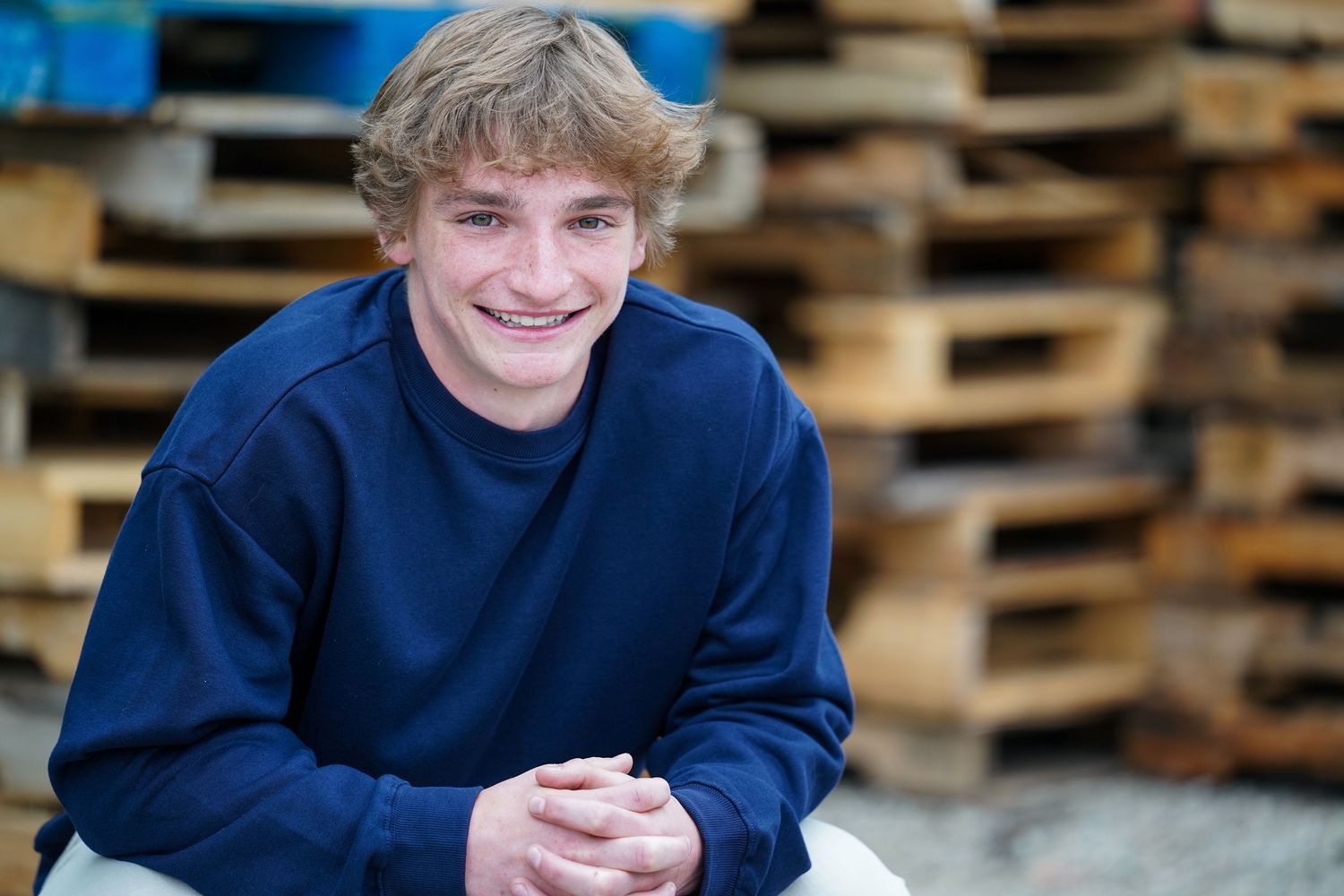 A headshot portrait photo of someone wearing a dark navy sweater while smiling warmly at the camera.