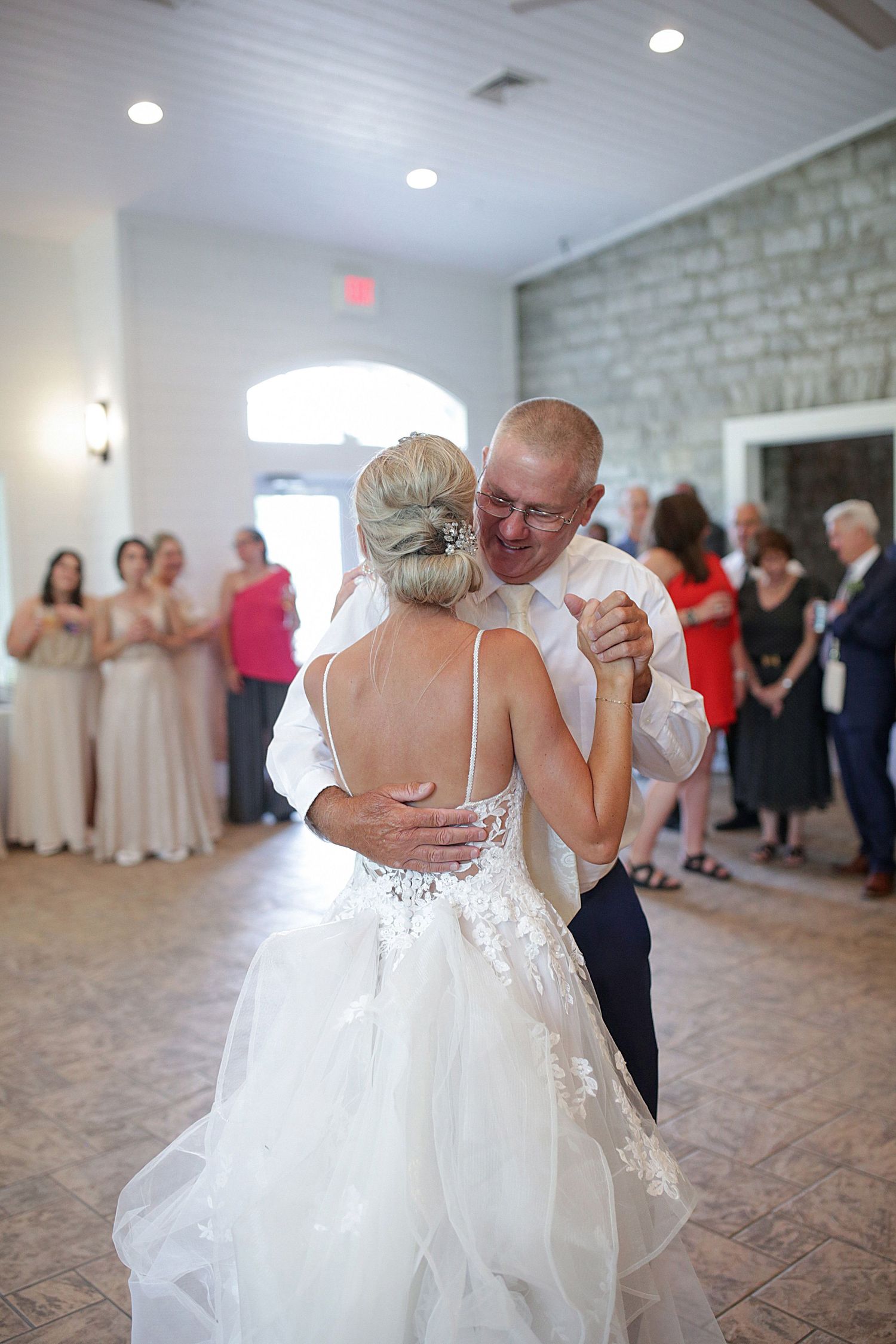 A couple shares their first dance in an elegant stone-walled reception venue.