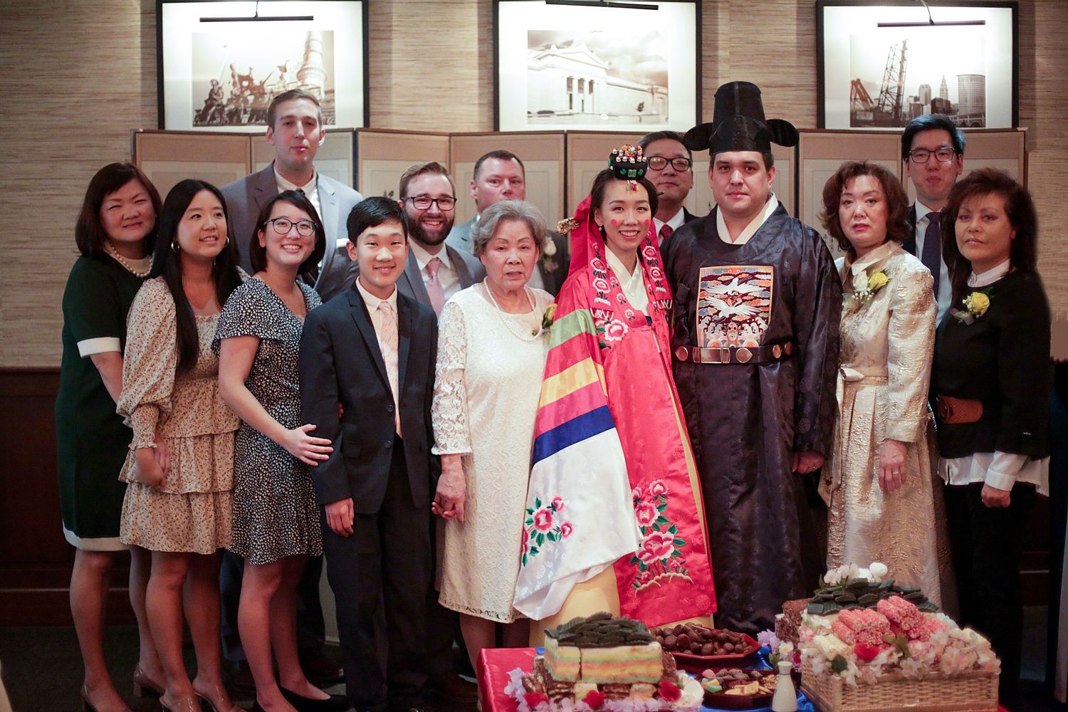 A group celebration with traditional Korean attire and formal outfits gathered together for a special occasion portrait.