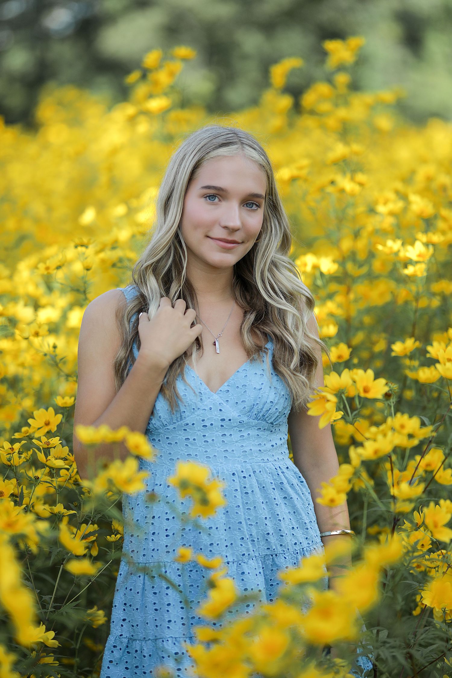 Beautiful outdoor portrait in a vibrant yellow wildflower meadow with someone wearing a light blue dress.