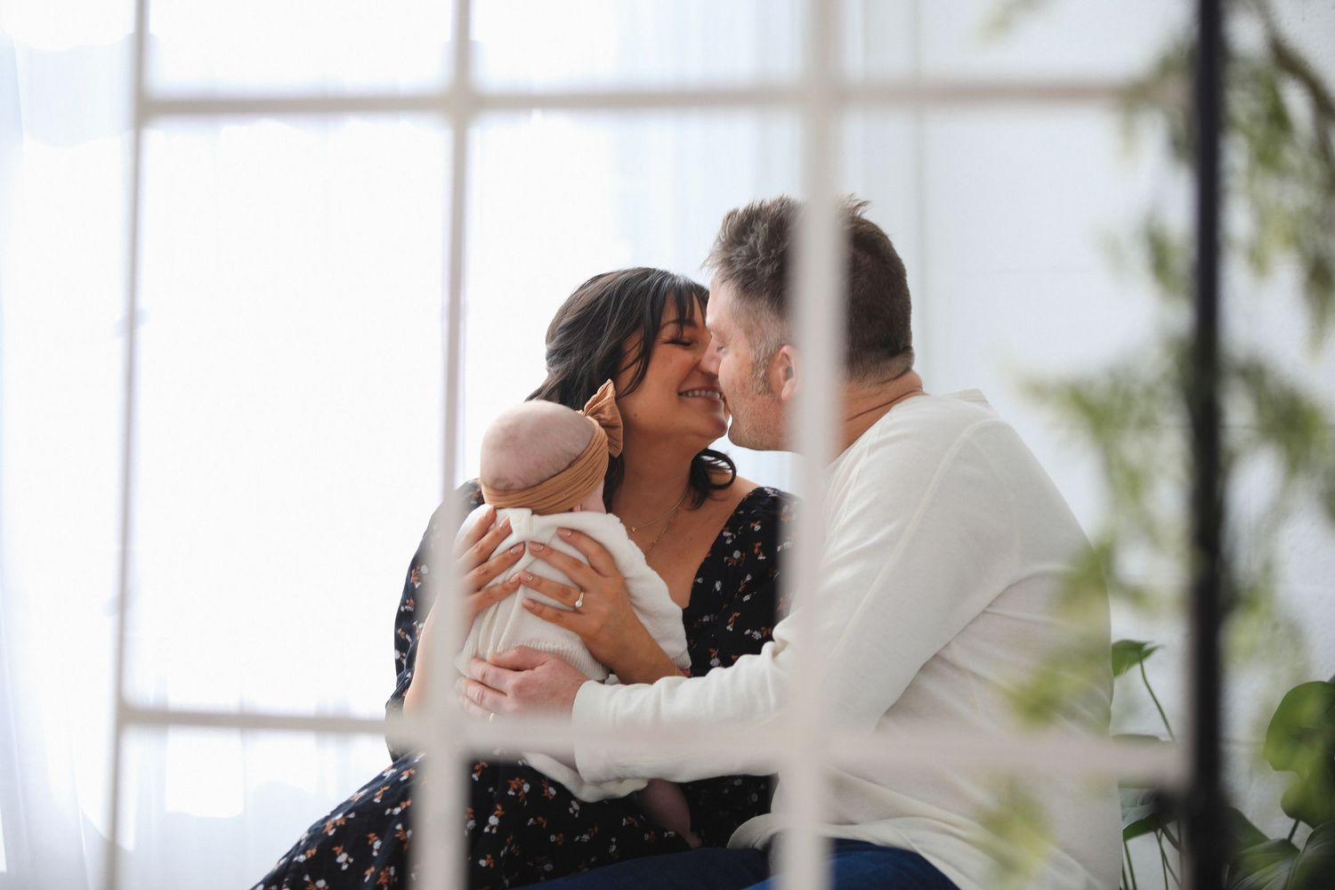 A romantic couple shares a tender dance moment in an elegant white room with large windows.