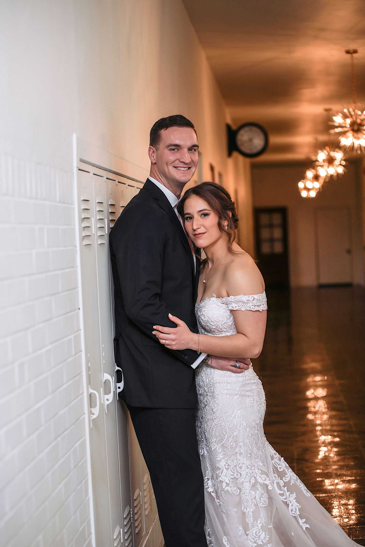 A romantic wedding photo series showing a couple posing together against a white brick wall with soft lighting.