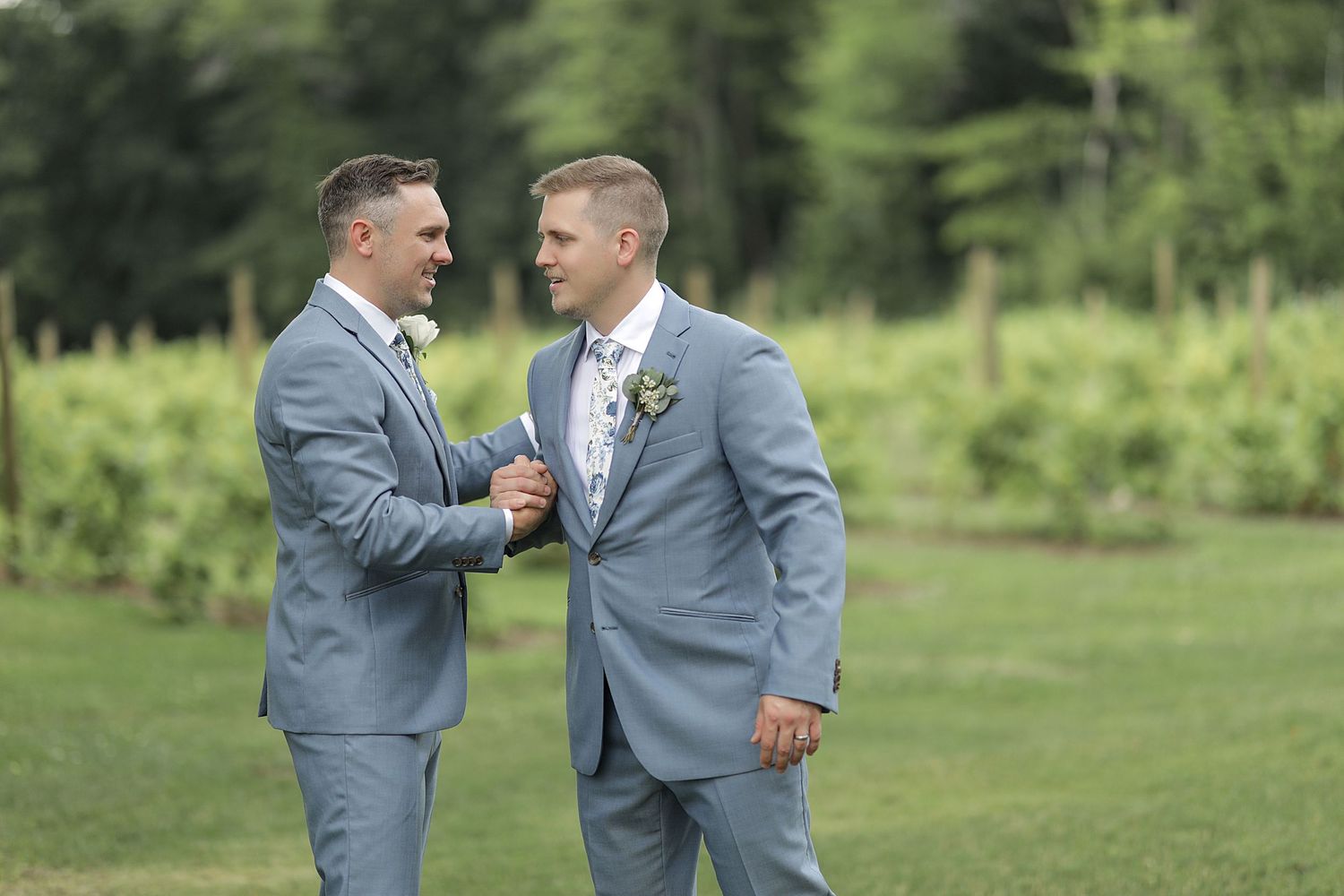 Groomsmen in light blue suits interacting outdoors during wedding photoshoot.