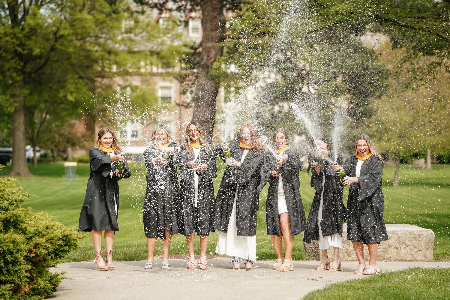 A group of bridesmaids in navy blue dresses pose together in a picturesque garden setting.