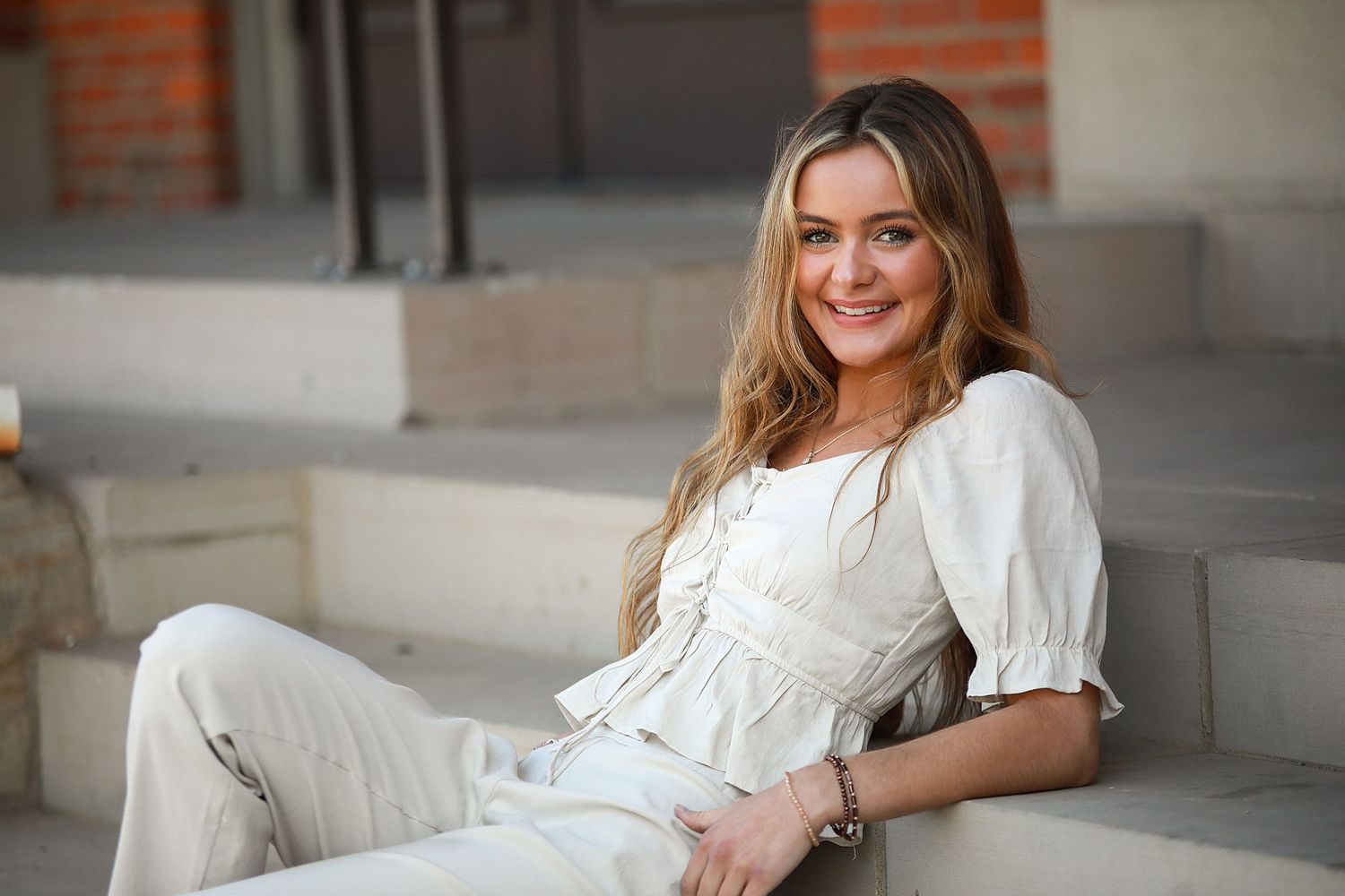 Senior Photography Medina Ohio. Relaxed portrait on stone steps featuring white cottagecore style outfit and natural lighting.