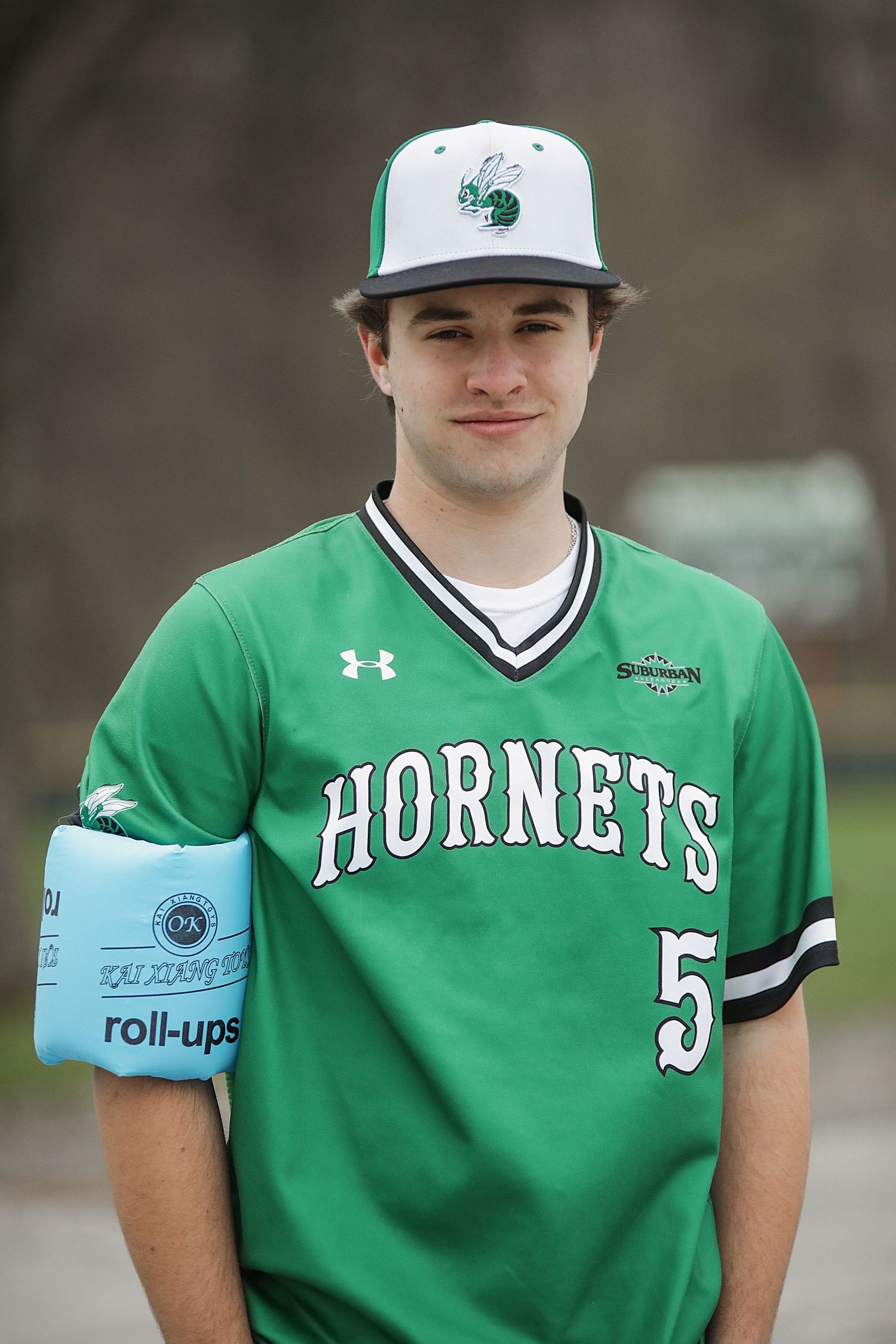 Baseball players in green Hornets uniforms stand together during a game showing team unity and sportsmanship.