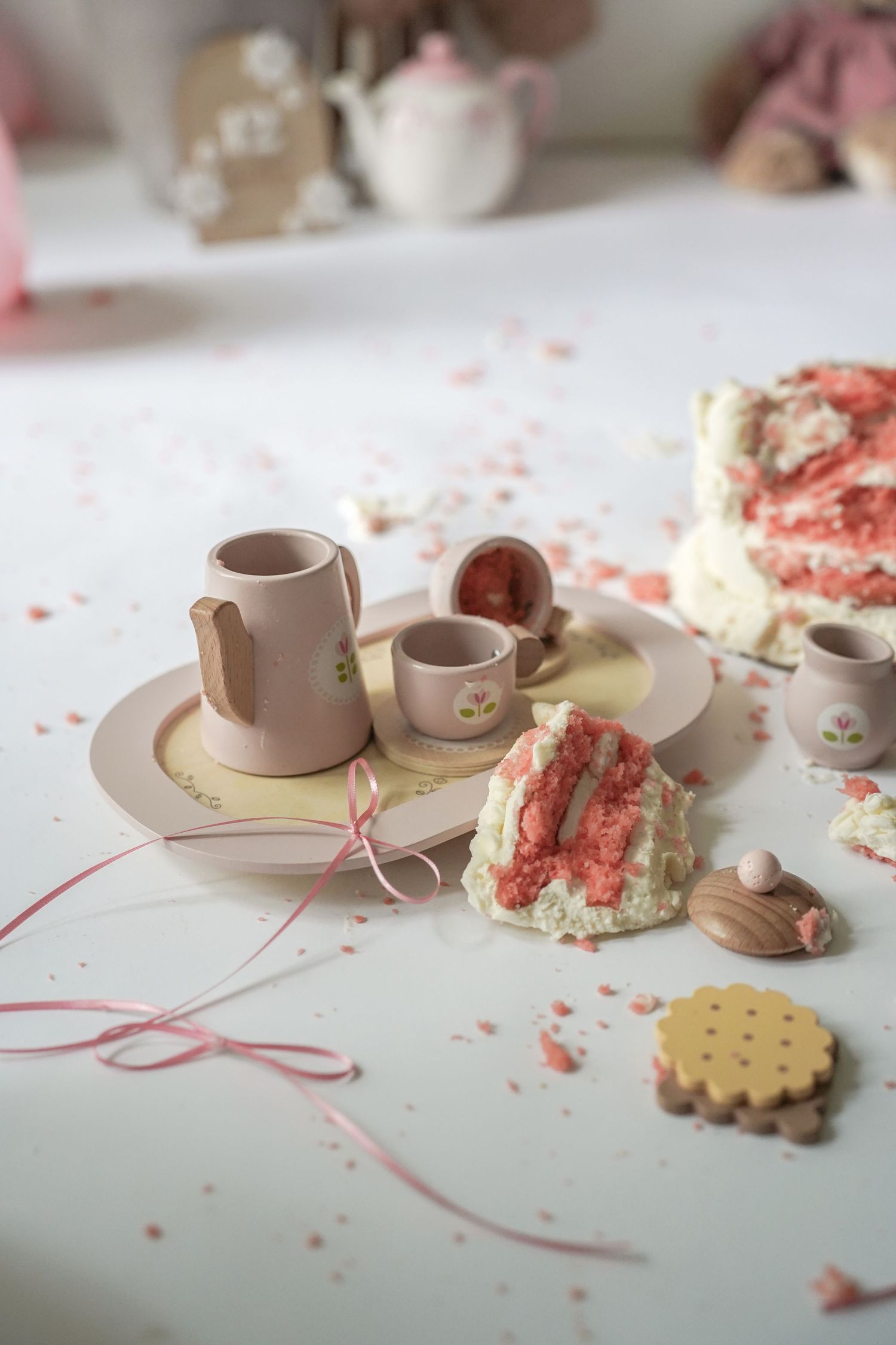Close-up photo series showing miniature clay tea sets and cookies with pink frosting crumbs on a light surface.