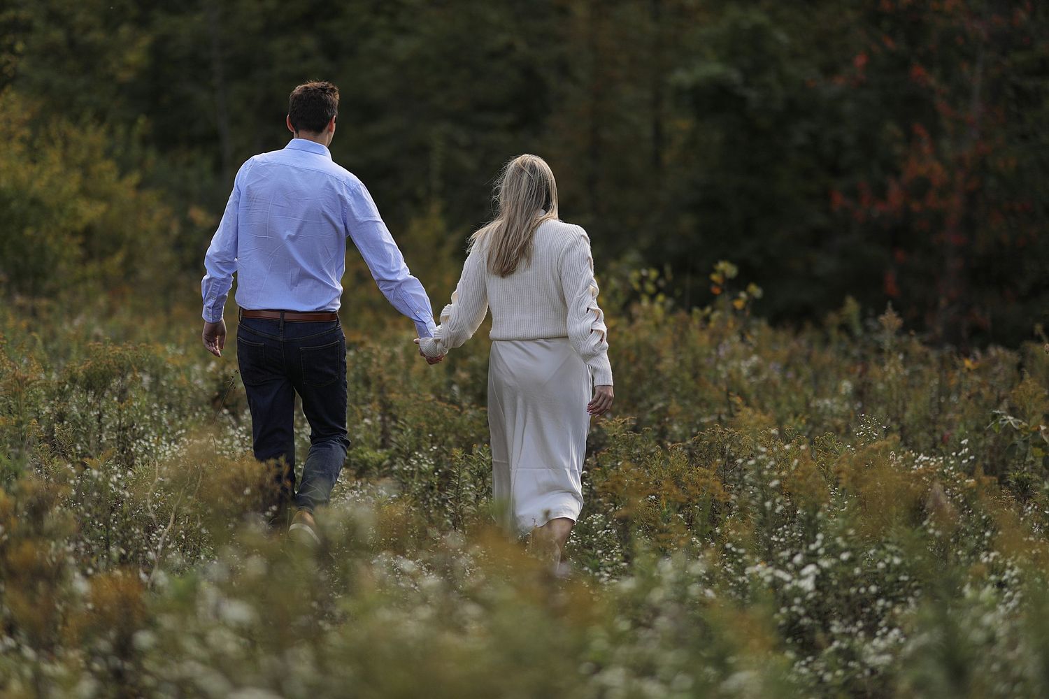 Two people walking through a wildflower meadow on a sunny autumn day.