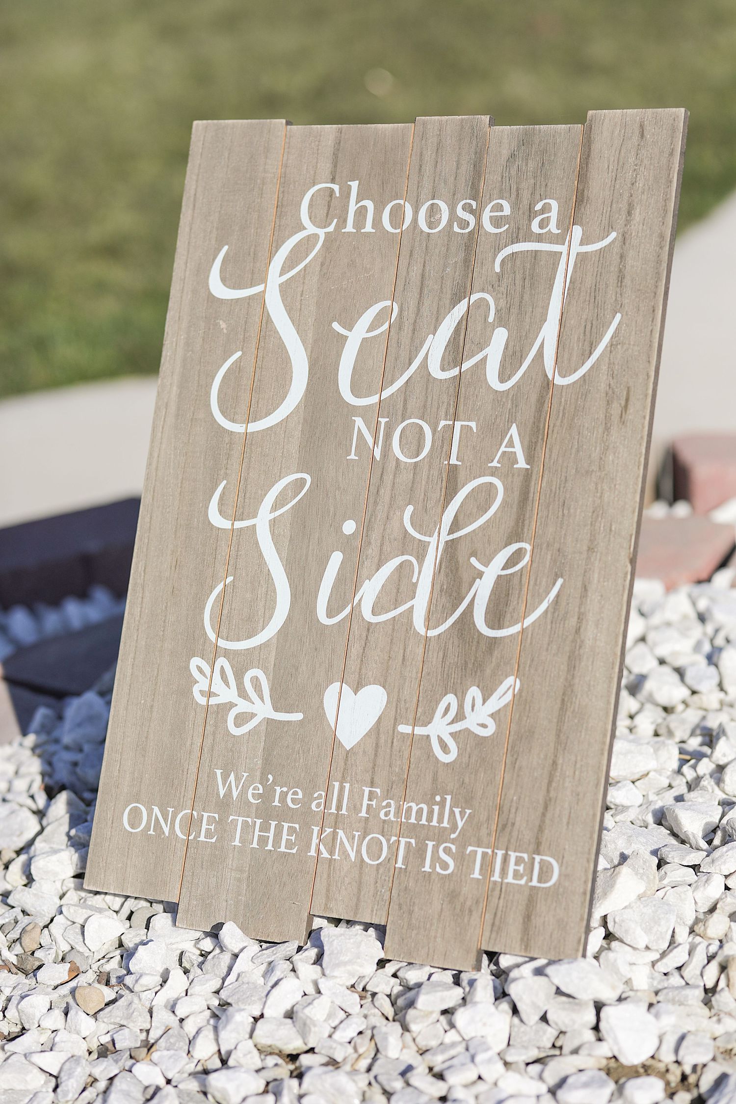 Rustic wooden wedding signs with white script lettering displayed on white decorative stones.