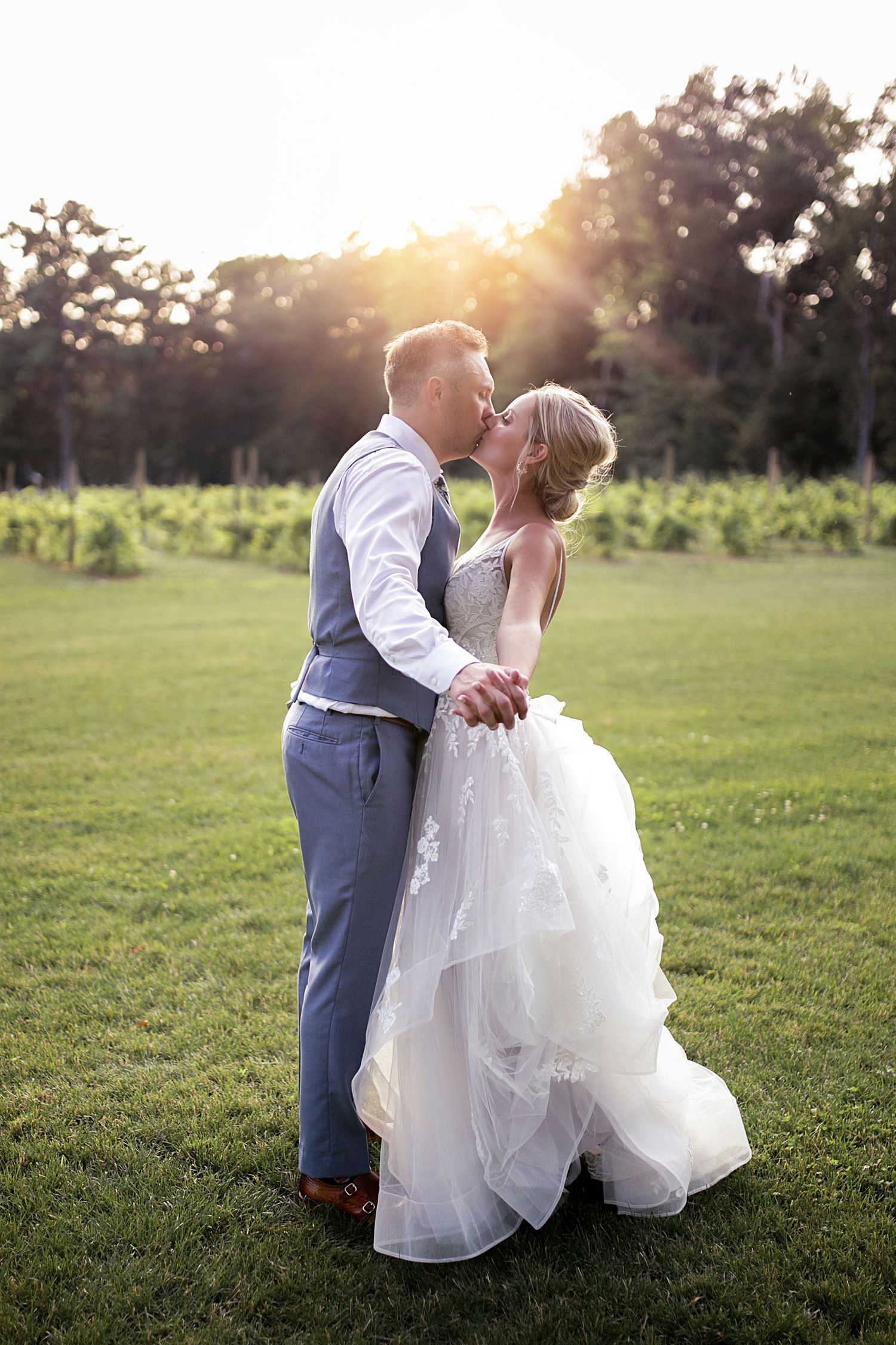 Sunset wedding portrait showing intimate moment between newlyweds on green lawn.