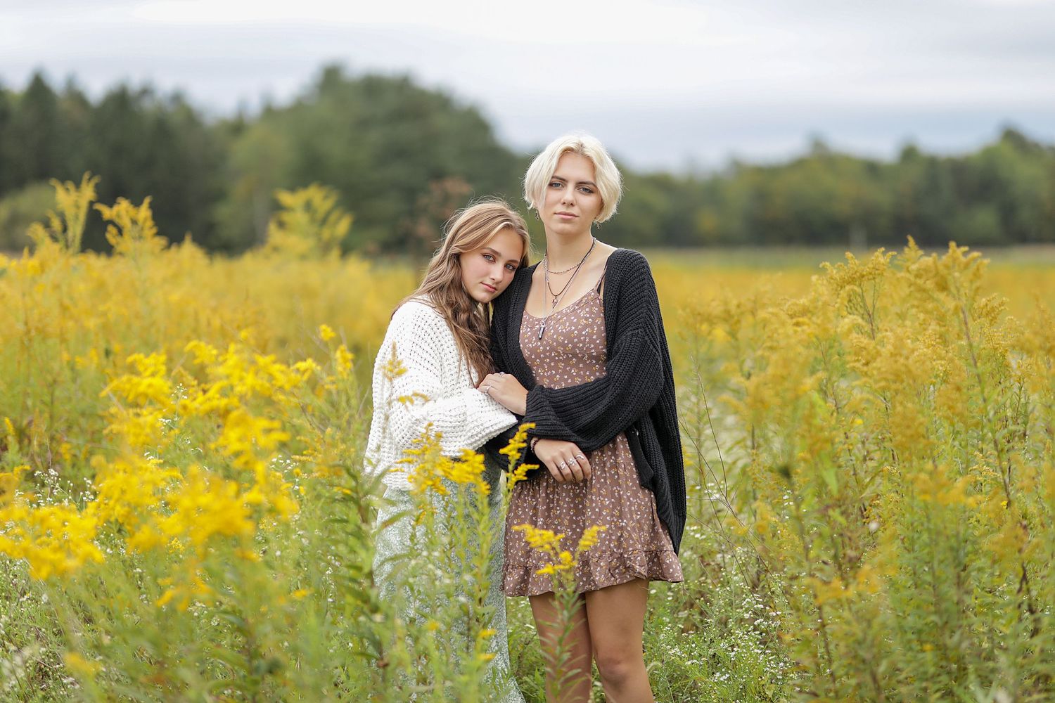 A couple embraces while standing in a vibrant yellow wildflower meadow on a sunny summer afternoon.