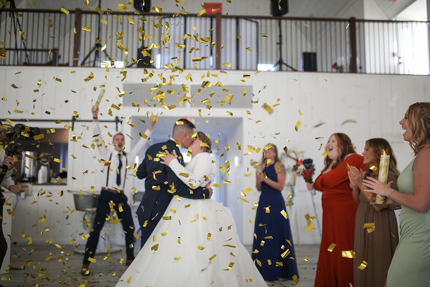Wedding party celebration with gold confetti being thrown inside industrial venue.
