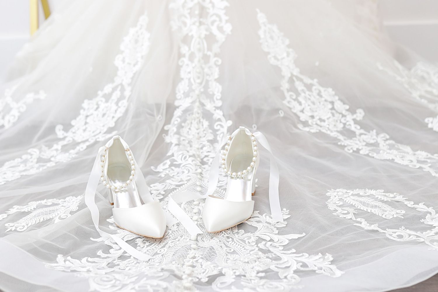Delicate white lace fabric and pearl embellishments create an elegant bridal or wedding detail texture.