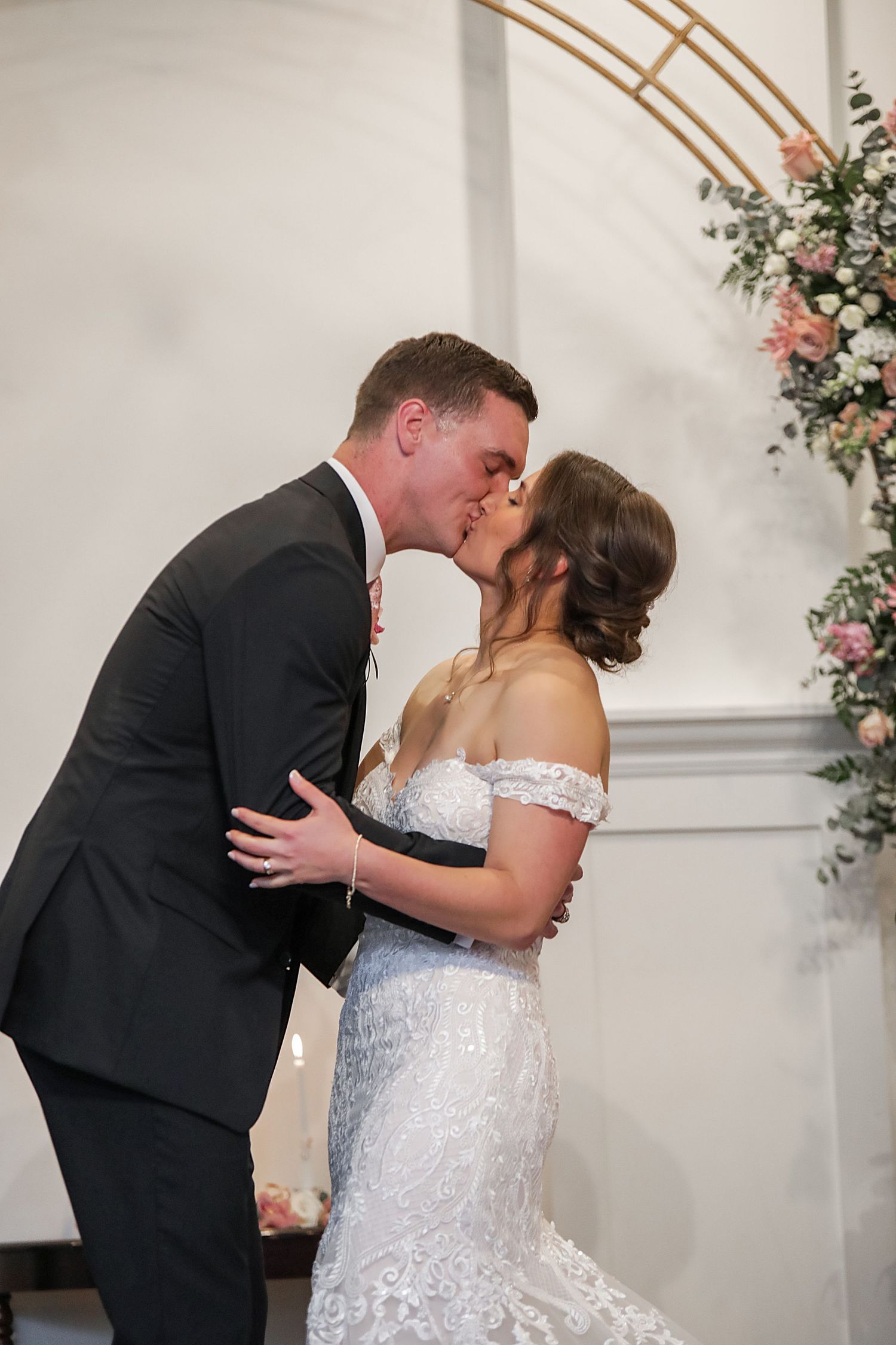 A romantic sequence of wedding photos showing a couple sharing their first kiss as newlyweds against a white wall.