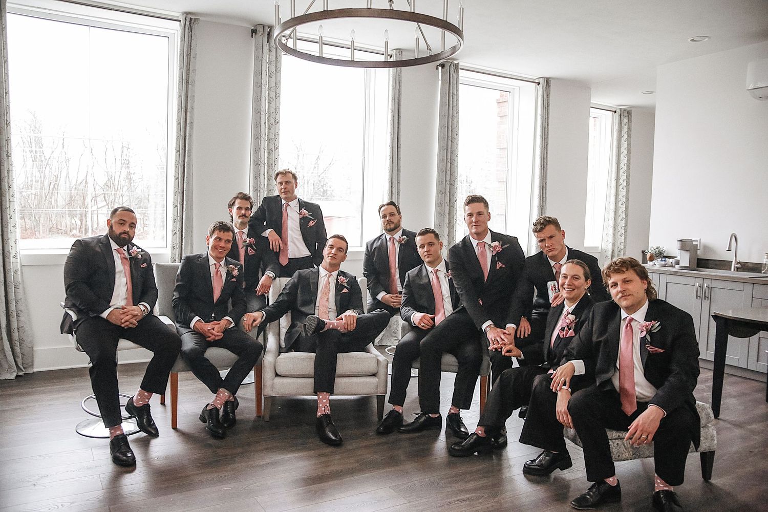 A creative wedding party photo sequence showing groomsmen progressively falling over like dominos in a modern indoor space.