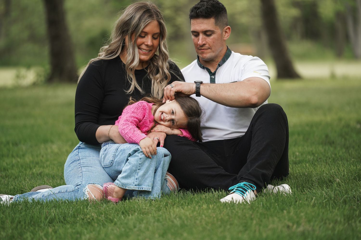 Family sitting together on grass in park during golden hour photoshoot.