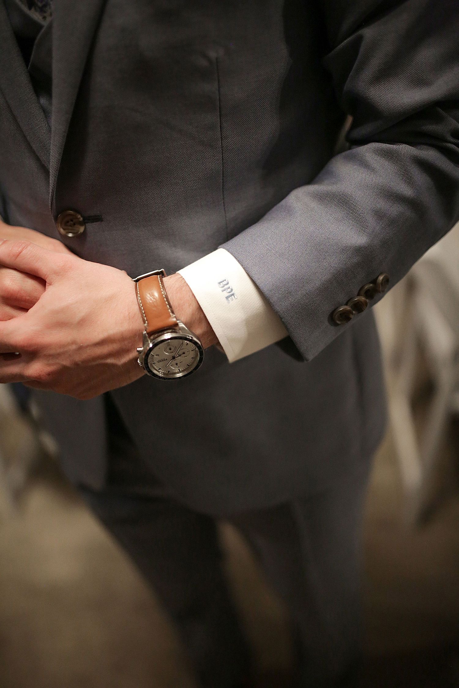 Close-up of groom's wrist showing classic watch and suit sleeve detail.
